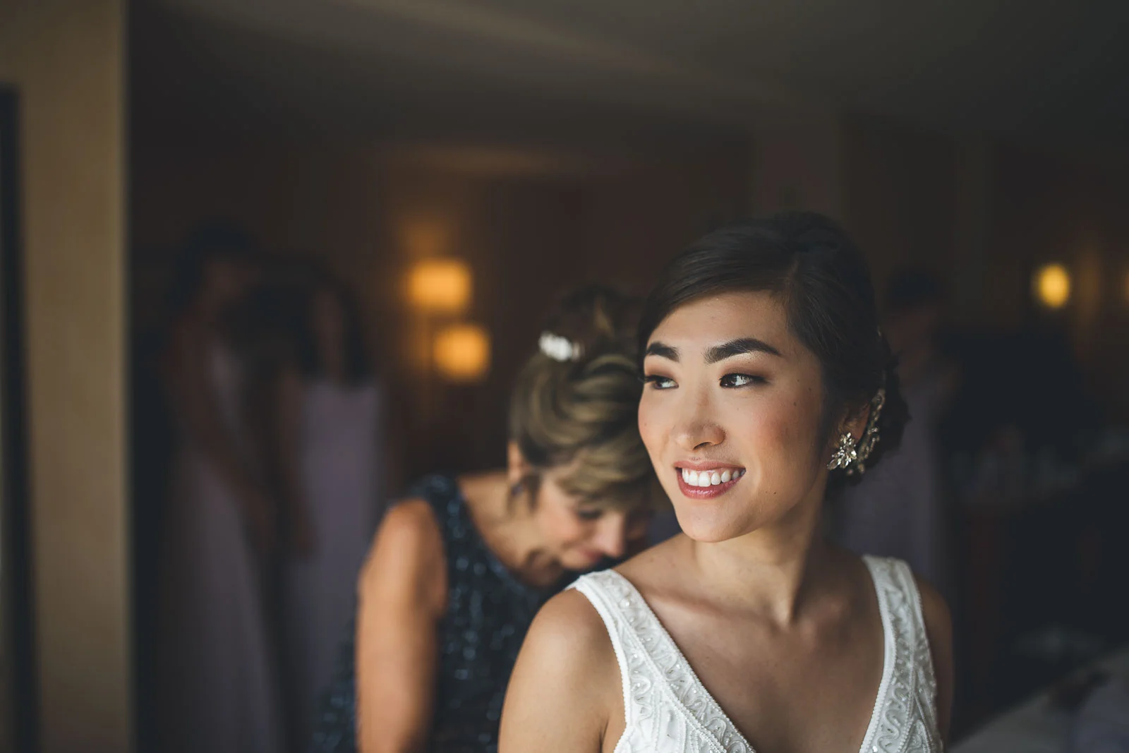 Bride gets dressed zipped up by Mom