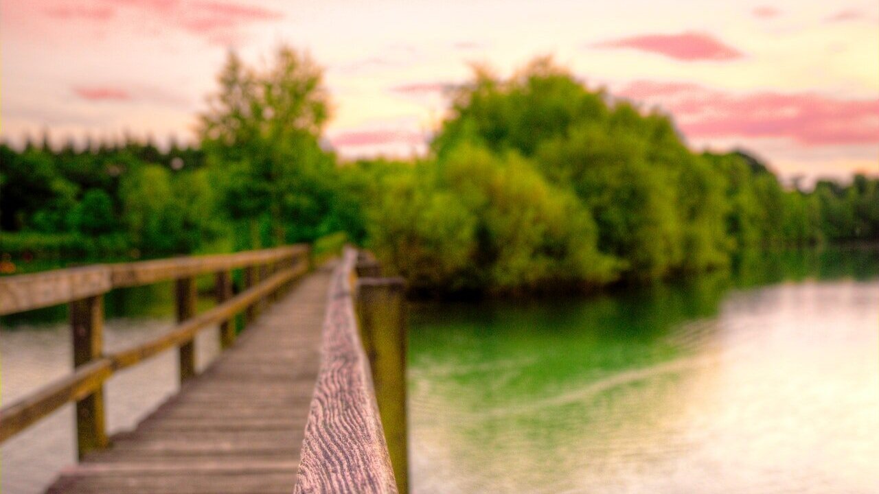 Photo of wooden bridge across water with pink sky by Skitterphoto from Pexels