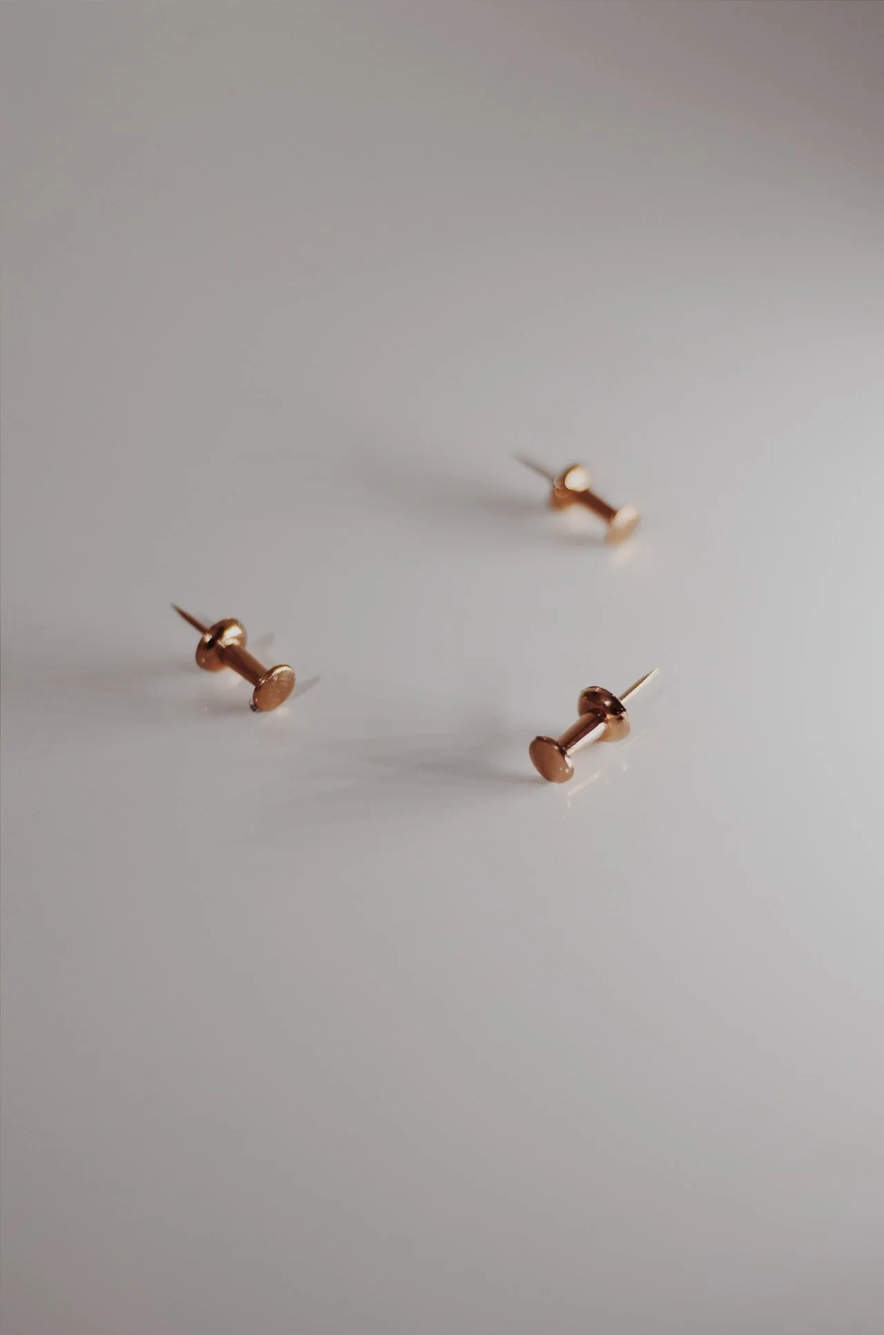 Photo of three gold tacks on white background by Ekrulila from Pexels