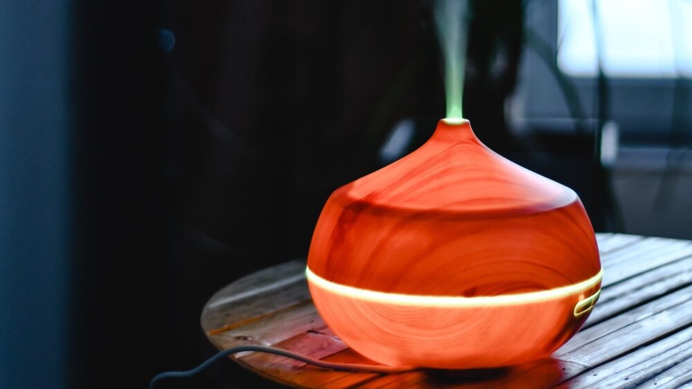 Photo of red-orange diffuser on wooden surface by Eva Elijas from Pexels