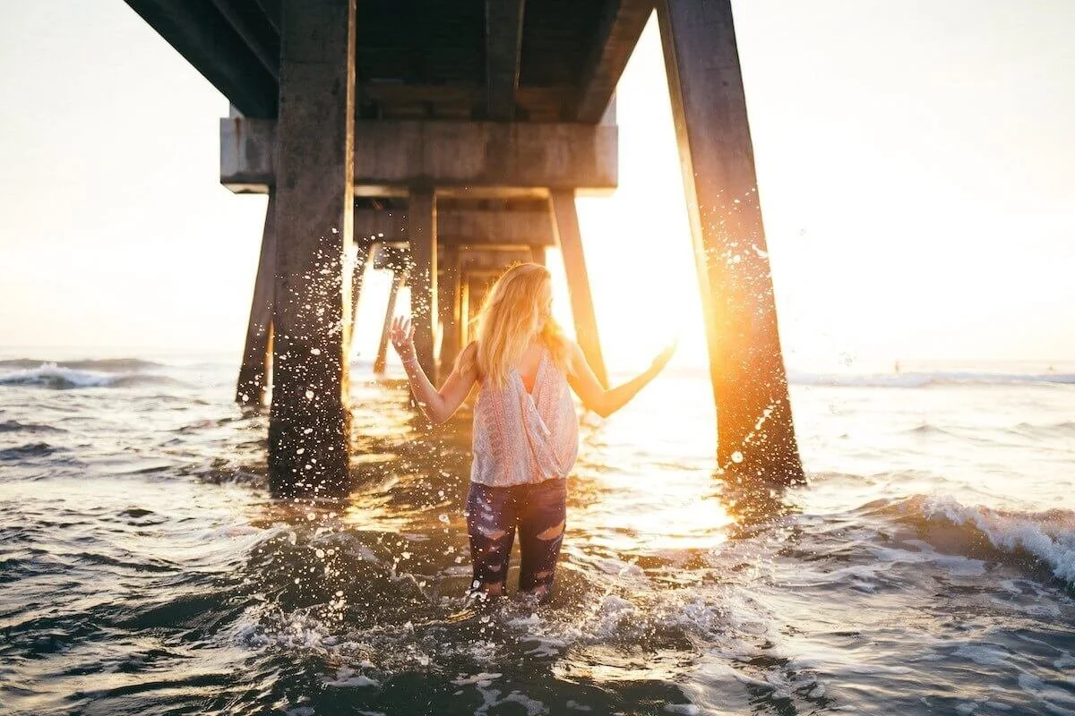 Photo of long haired person in golden hour playfully splashing water by Seth Doyle on Unsplash