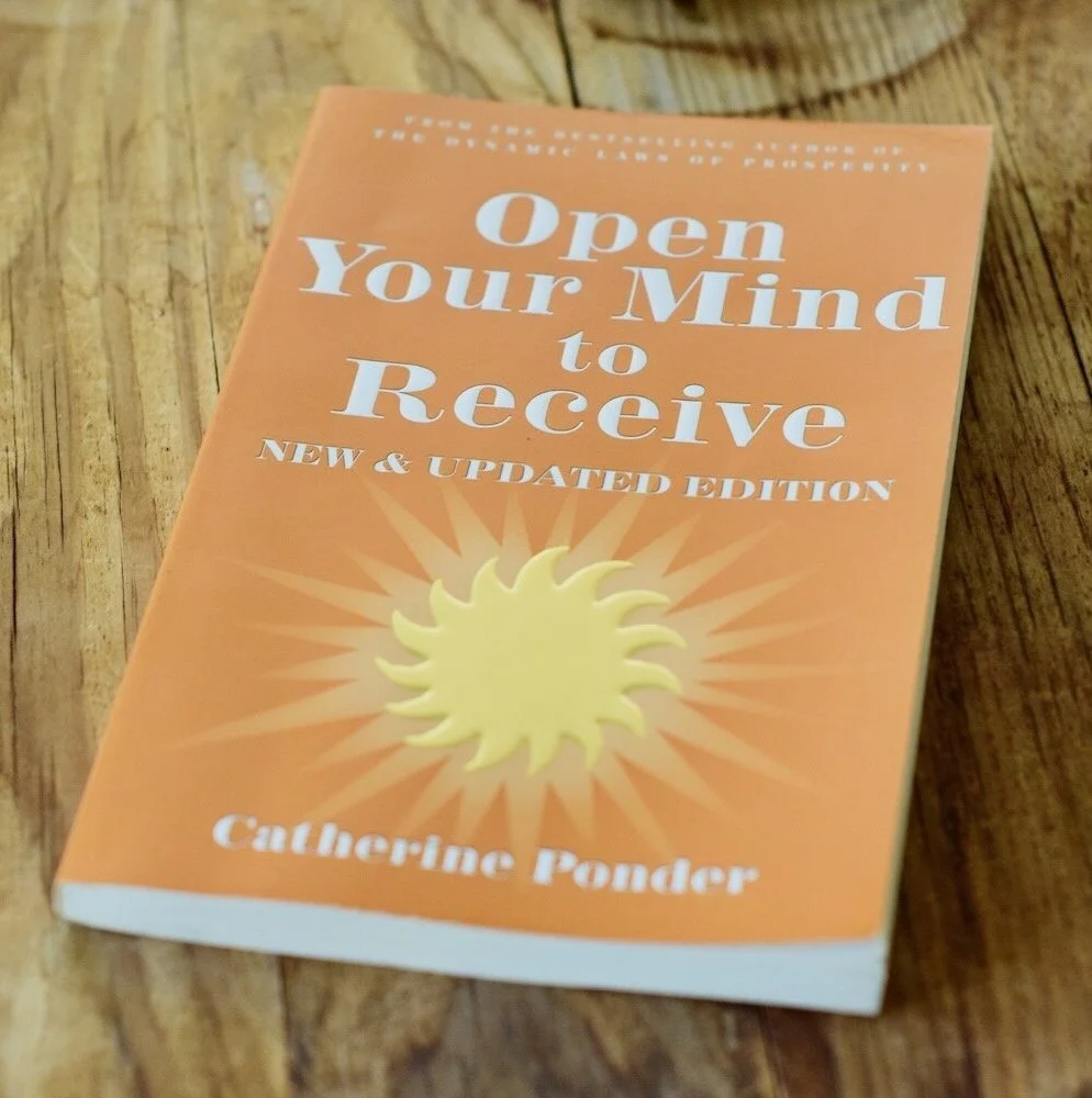Photo of book, Open Your Mind to Receive by Catherine Ponder on wooden table by Amanda Linette Meder
