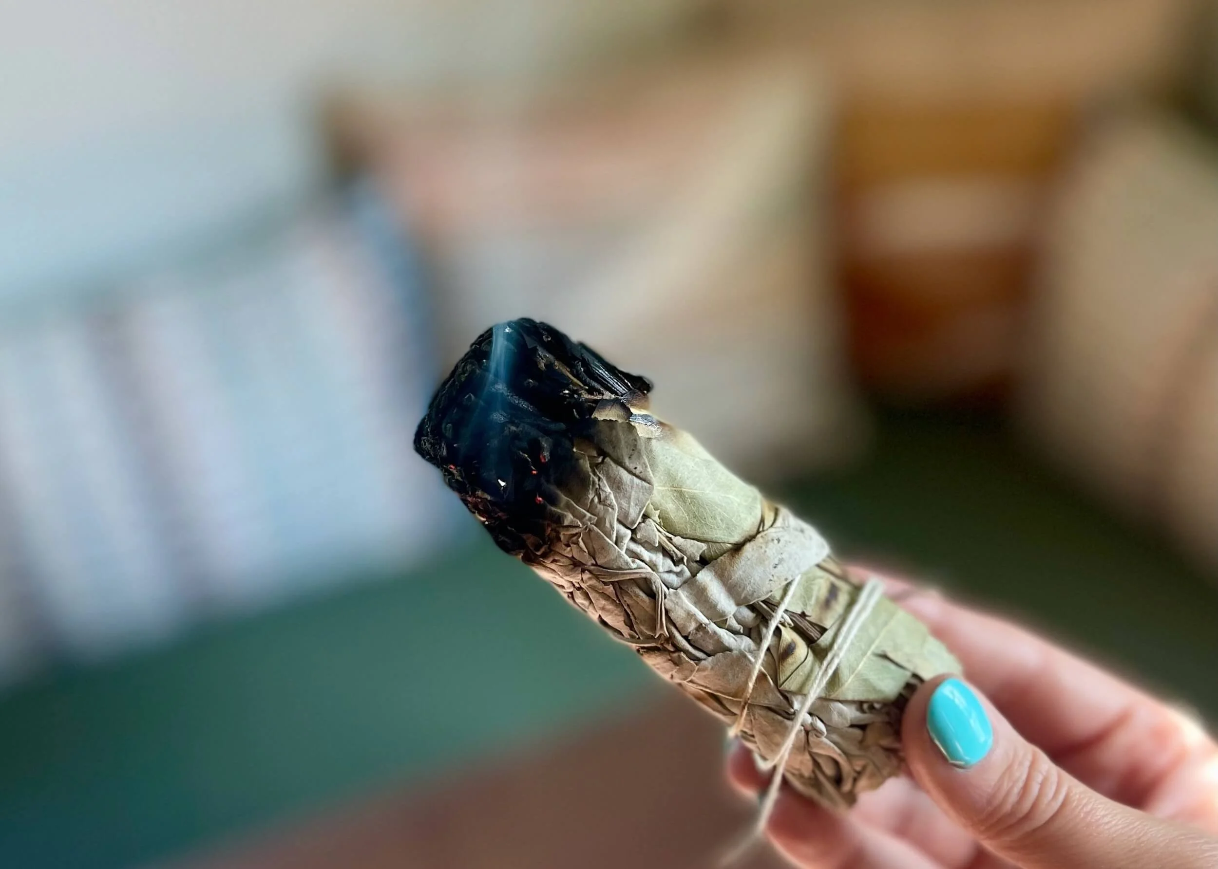 Photo of self holding a burning sage wand that you use in smudging