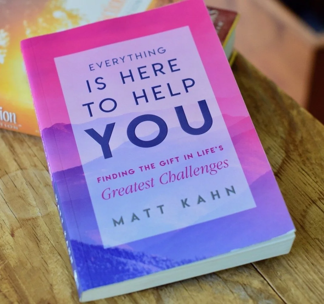 Photo of book, Everything Is Here To Help You, propped up on The Essential Law of Attraction book on wooden table with chest in background, by Amanda Linette Meder