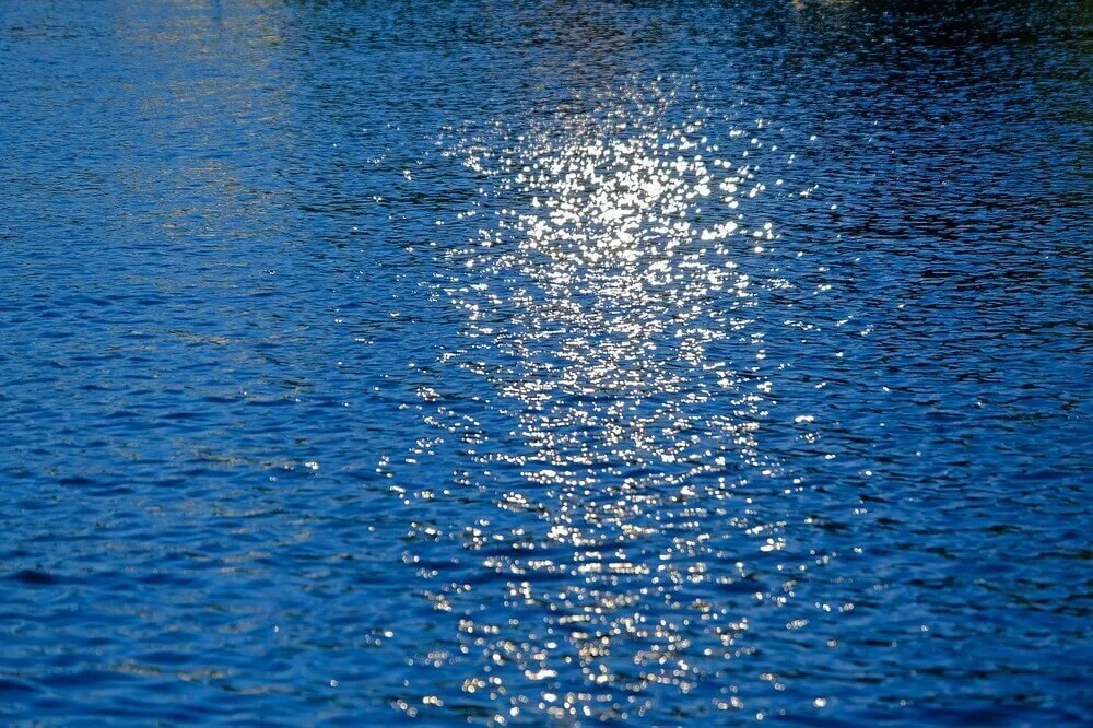 Photo of glittering light on water’s surface by NickyPe from Pixabay