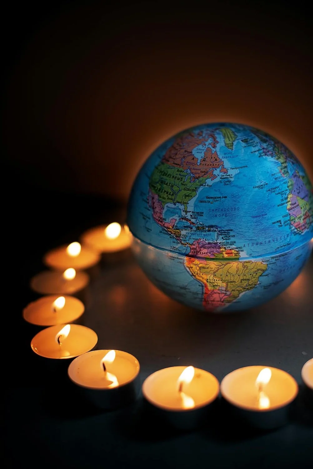 Photo of tea lights around globe by Mikhail Nilov on Pexels