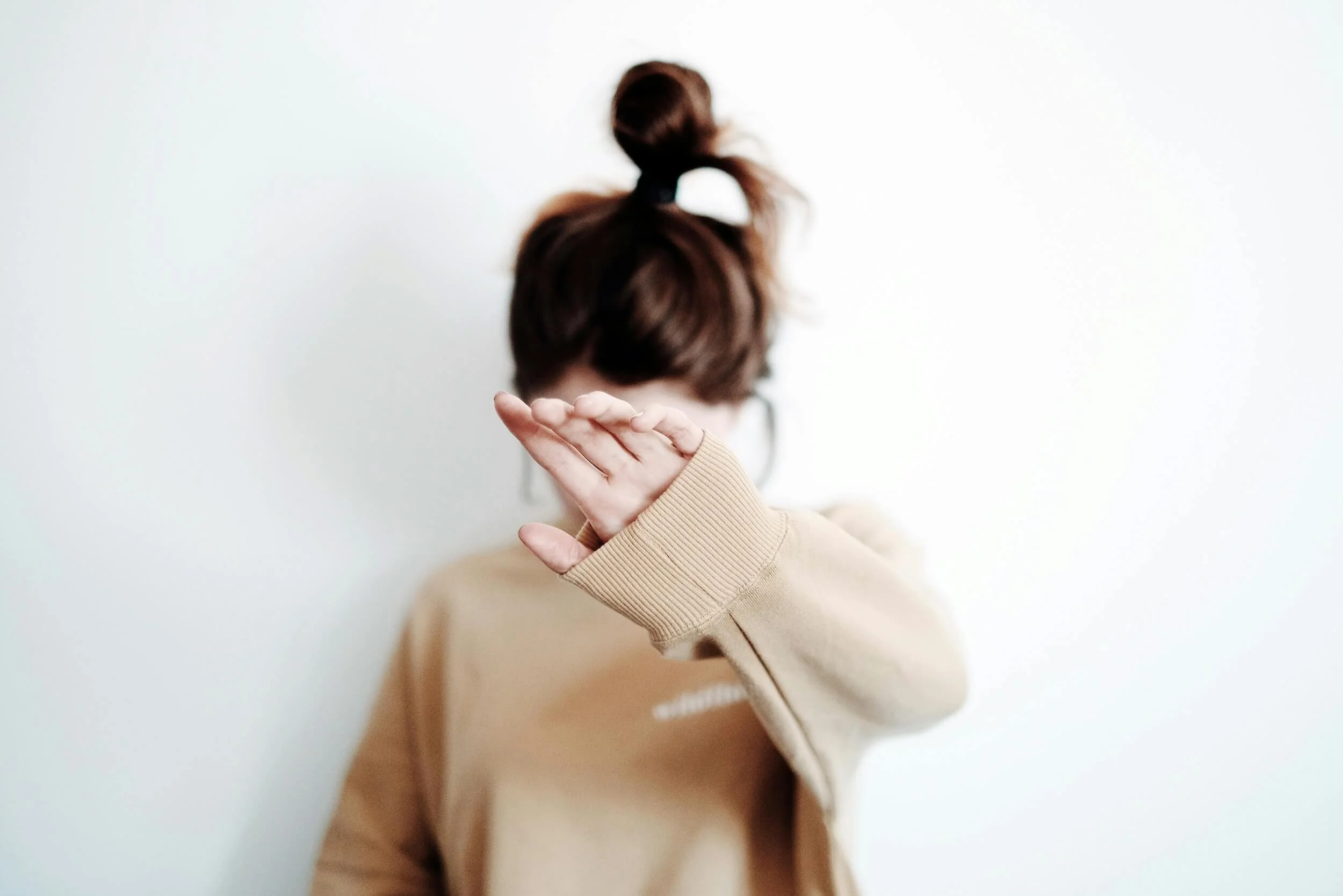Photo of woman with hand up in beige sweatshirt by Vie Studio on Pexels