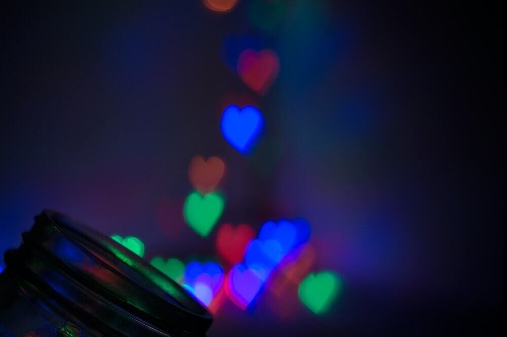 Photo of heart shaped lights on blue background with jar top in corner appearing to capture the hearts by Joshua Slate from Pexels