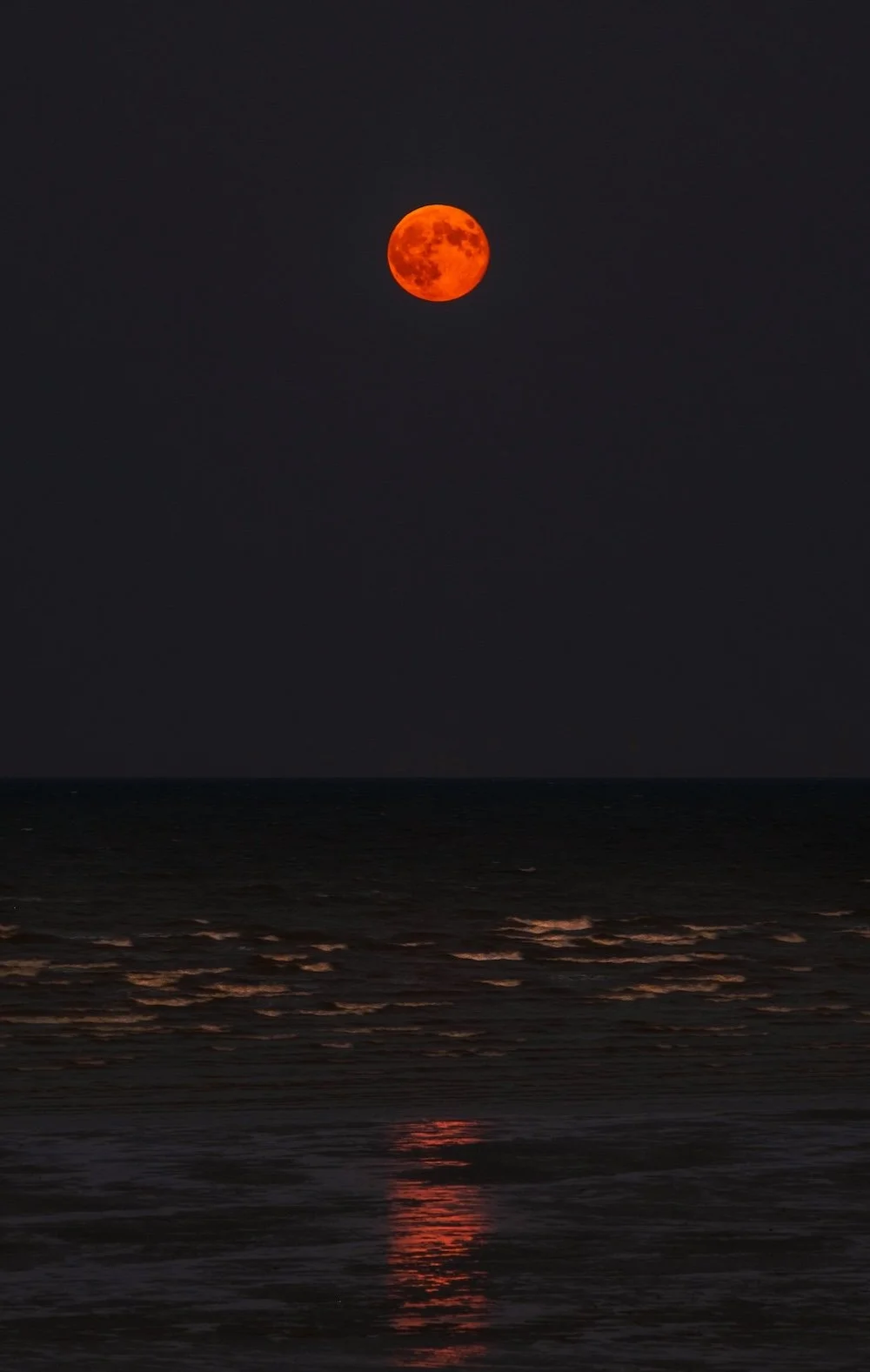 Red moon over glowing water by Zoltan Tasi on Unsplash