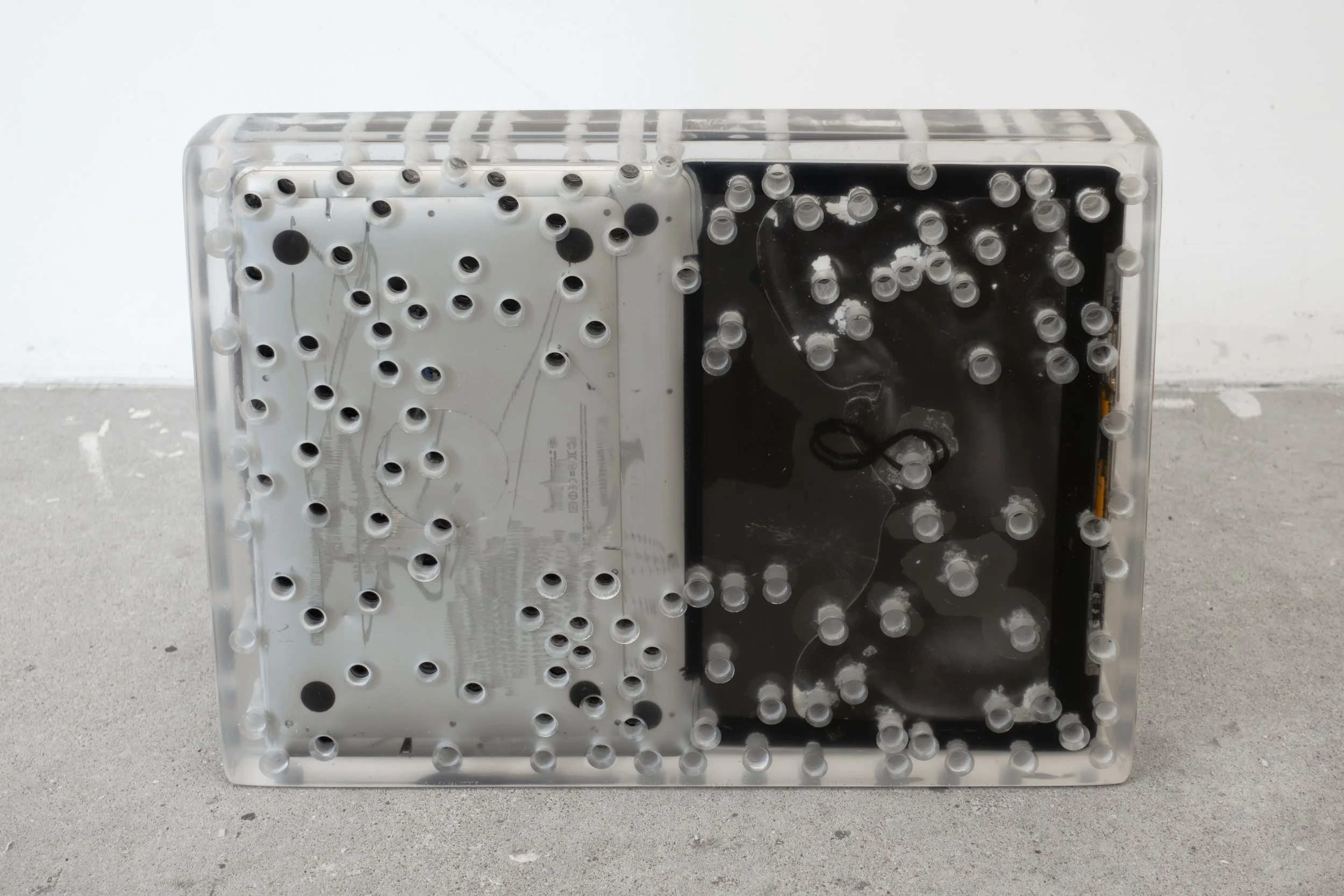  JASON GRINGLER.  EBAY SCULPTURE (PACKAGE) (2024).  STUDIO VIEW.  LAPTOPS, PACKING TAPE, CARDBOARD, HOLES, WOOD, SILICONE, DETRITUS, EPOXY RESIN.  48 X 35 X 6 CM (19 X 14 X 2 1/2 IN) UNIQUE. 