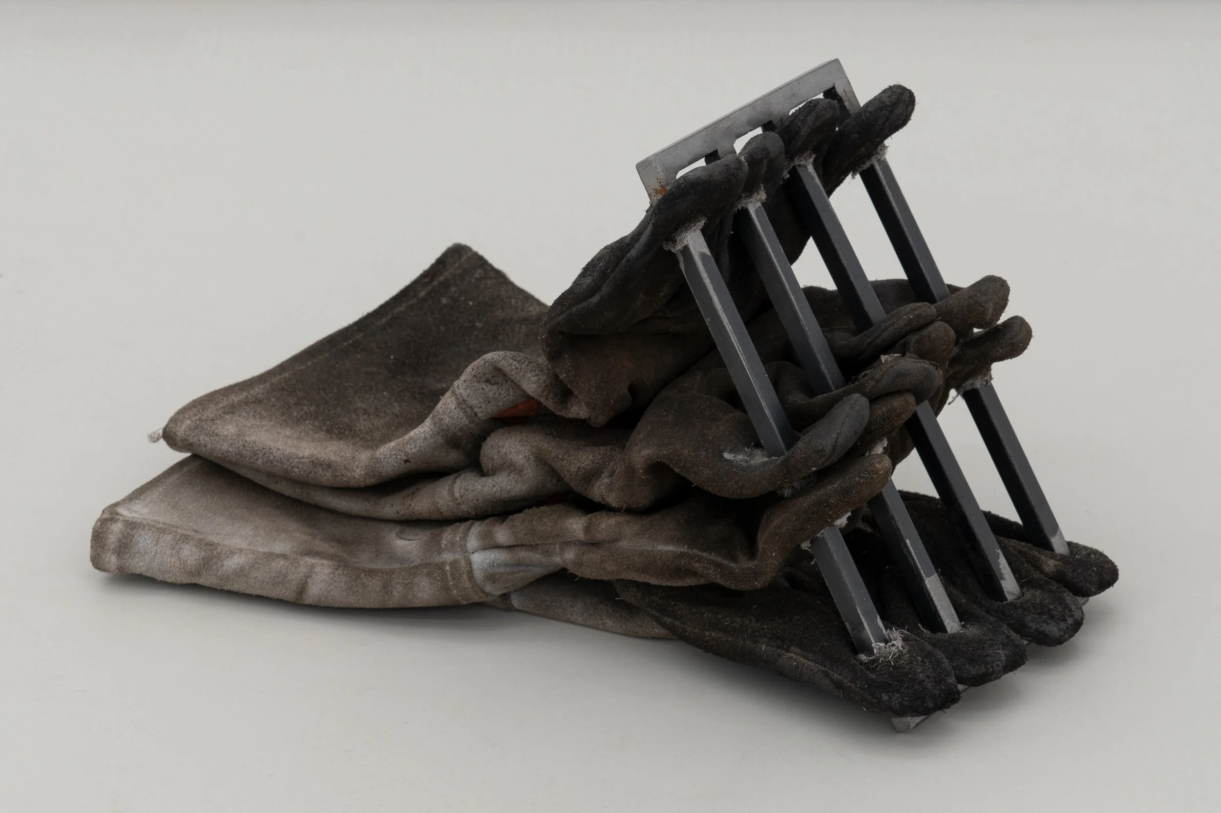  JASON GRINGLER.  USED WELDING GLOVE PRISON (2022).  'INAUGURATION' LO BRUTTO STAHL, PARIS. APRIL 1 - JUNE 3 2023.  GLOVES, STEEL, DIRT.  VARIABLE DIMENSIONS. UNIQUE. 
