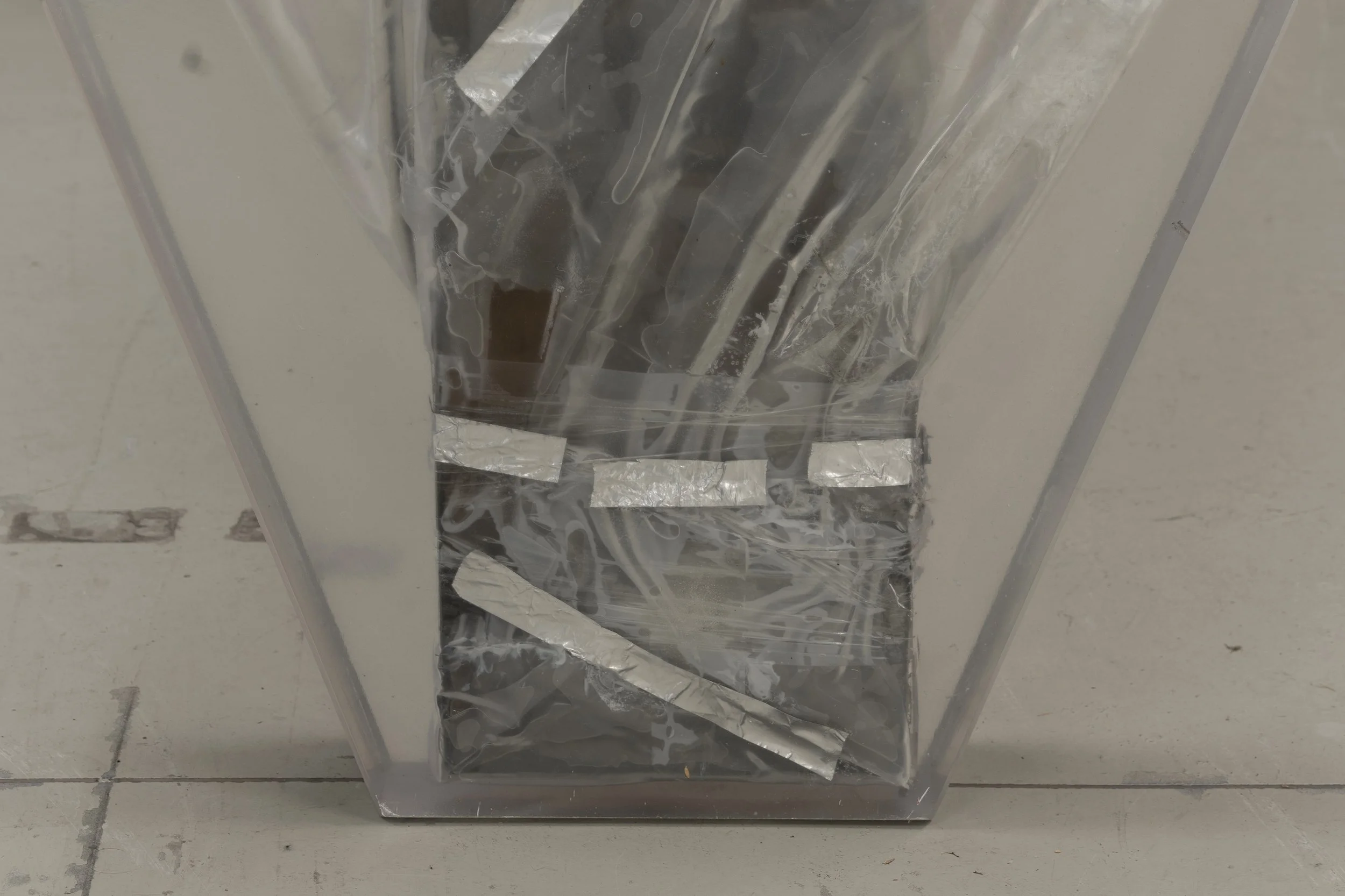  JASON GRINGLER.  TOMB (2026) (DETAIL).  'AIR SERVICE' LO BRUTTO STAHL, BASEL. JUNE 15 - JUNE 21 2026.  FAILED ARTWORK, ALUMINUM TAPE, CARDBOARD, STEEL, PLASTIC WRAP, ADHESIVES, PACKING TAPE, EPOXY, DETRITUS AND WAX.  11 X 85 X 125 CM. 