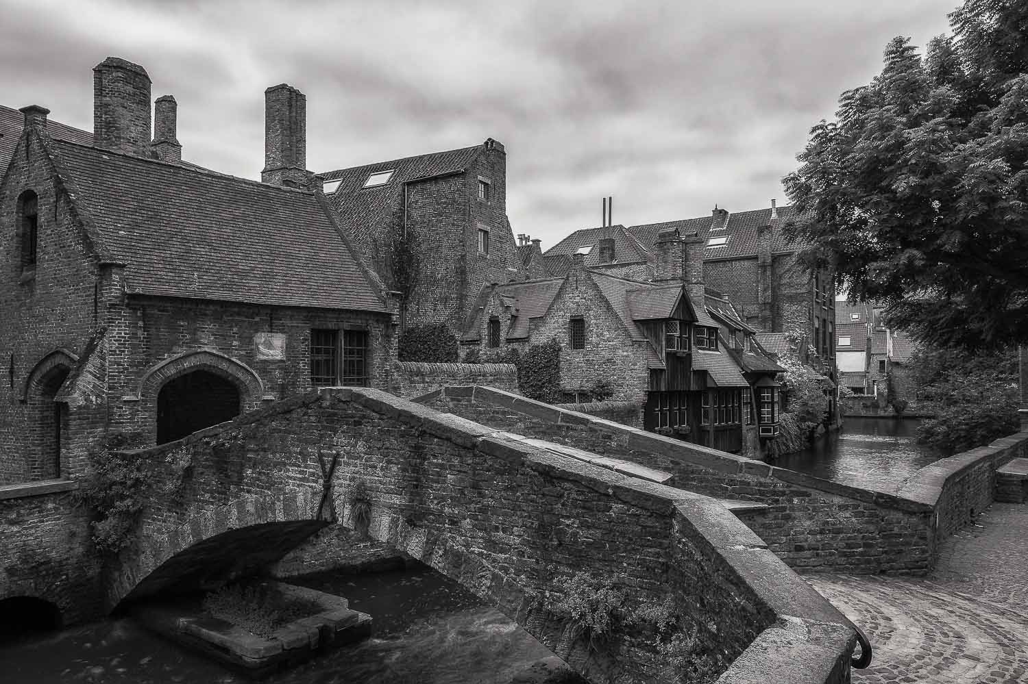 Shapes and texture dominate this black and white photo of a footbridge crossing a canal in the historical city of Brugge, Belgium.