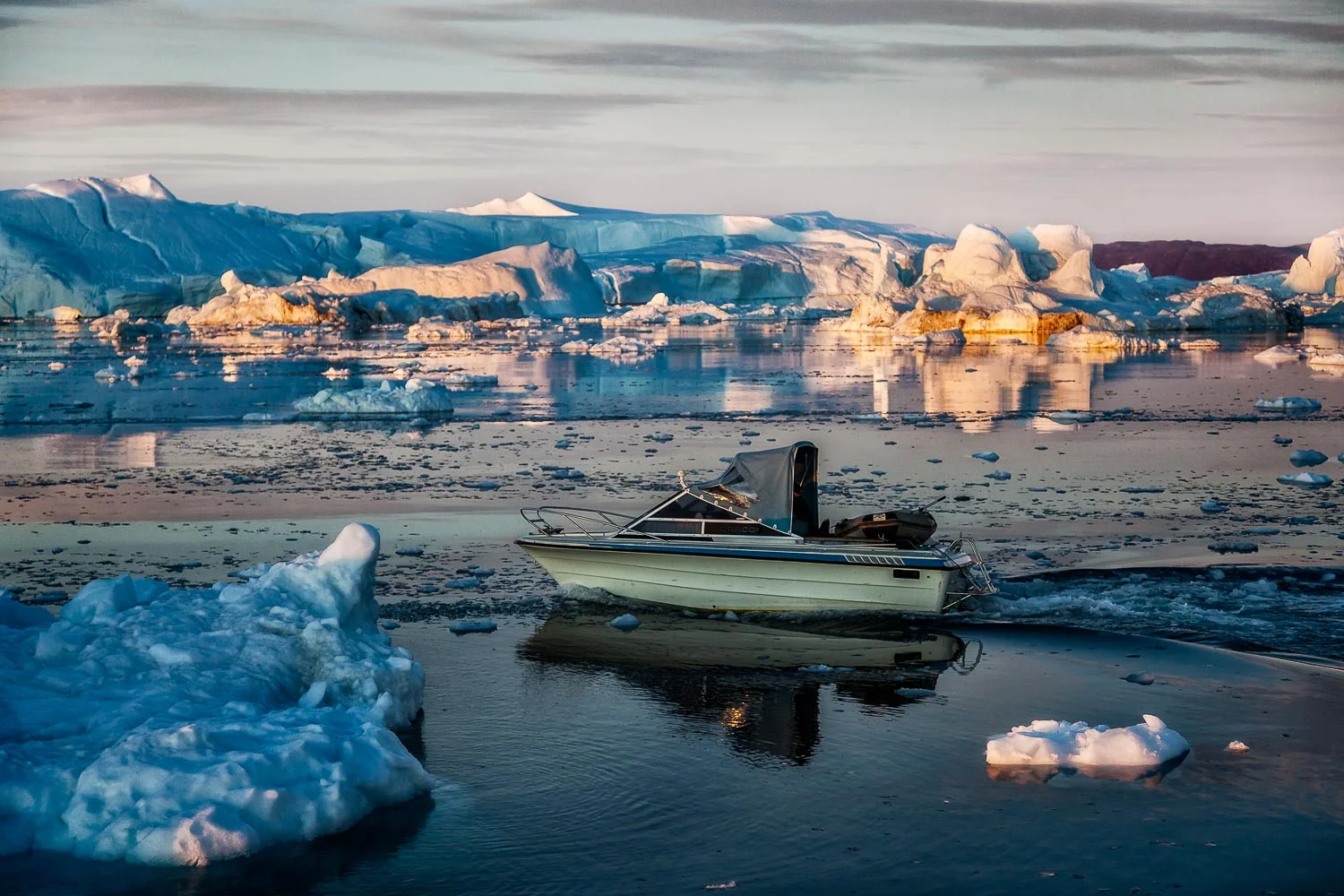 A small fishing boat heads out onto the waters of the Ilulissat Icefjord near Ilulissat, Greenland.