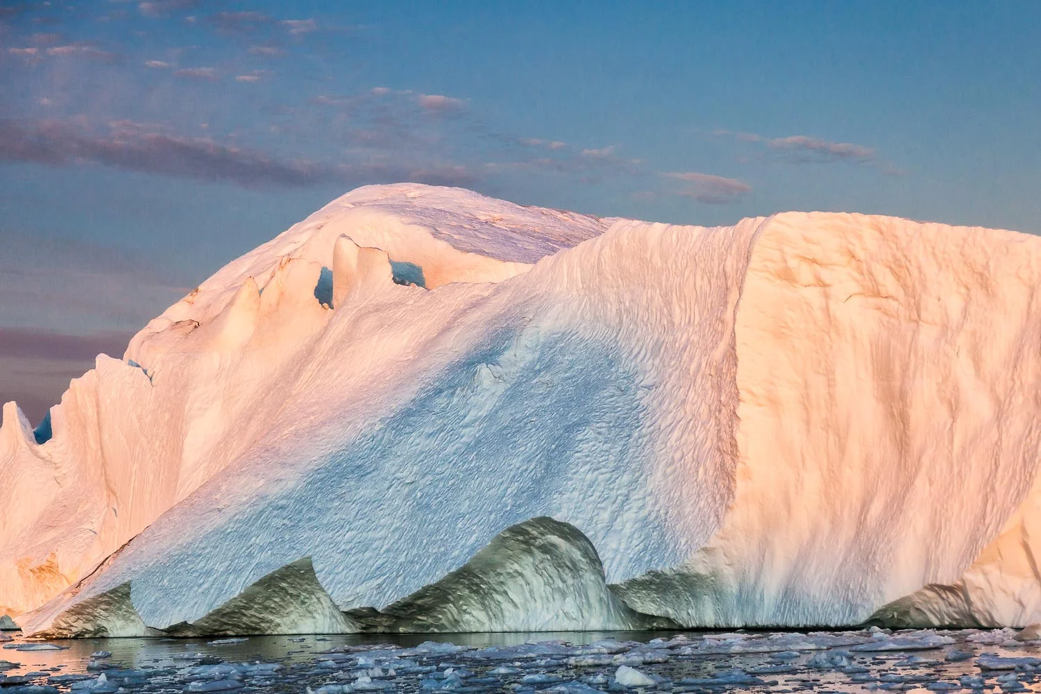 The dramatic colors and textures of this huge iceberg are emphasized under the light of the midnight sun on the Ilulissat Icefjord near Ilulissat, Greenland.