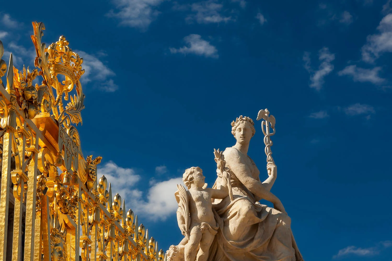 Striking light illuminates statues and the golden gate at the Palace of Versailles, France