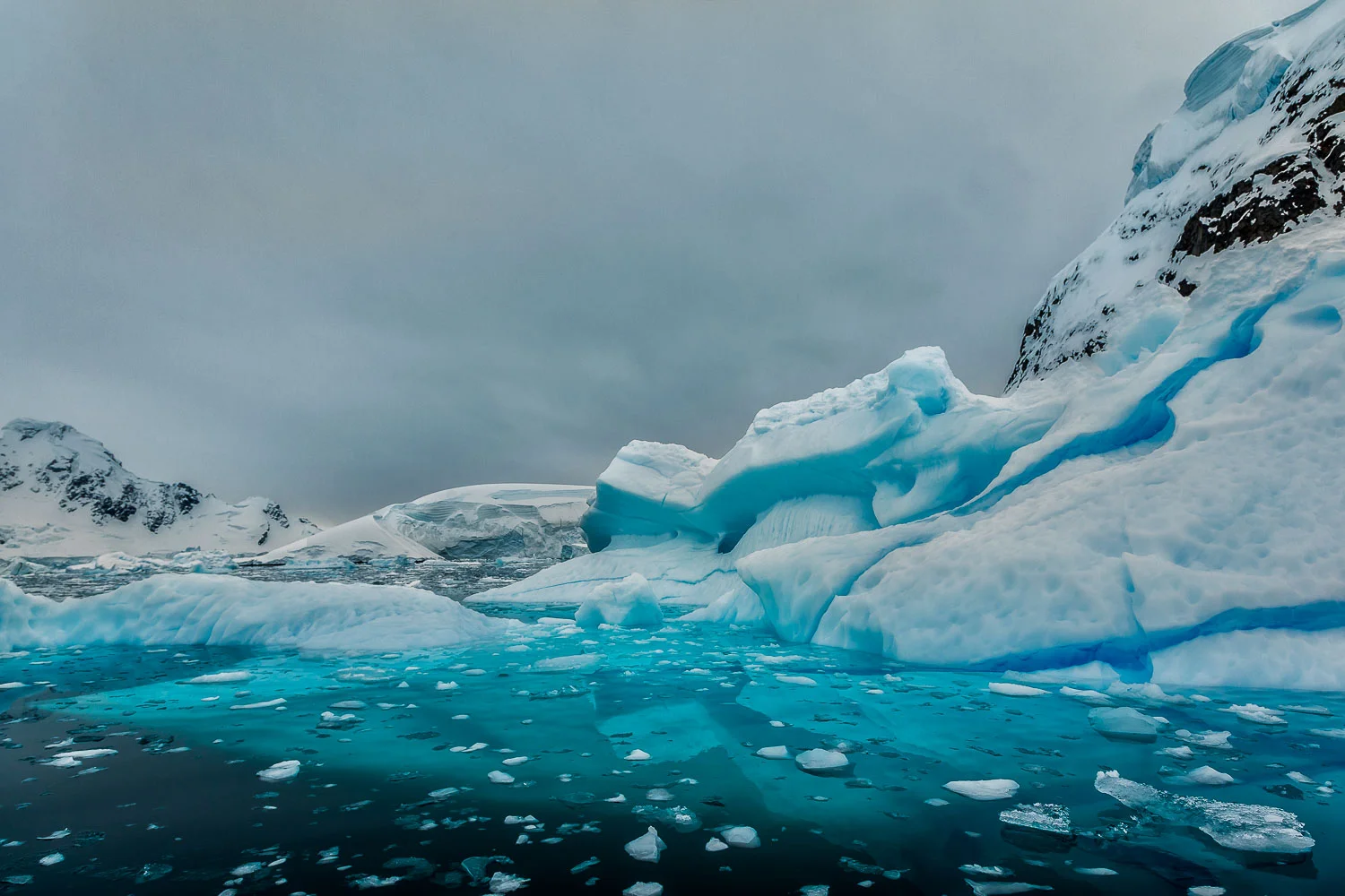 The cool blue of an overcast sky, ice and water make for a particularly melancholy mood of ice and snow on Paradise Harbour, Antarctica .