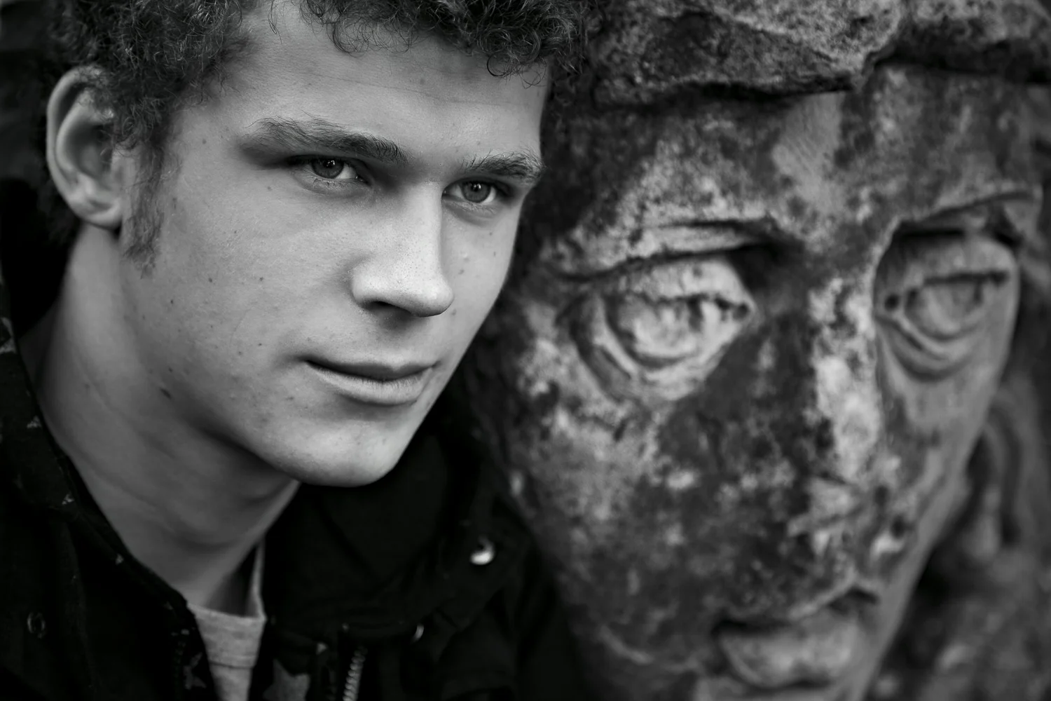 A close up portrait of a young man alongside a statue in Eltham, Australia.