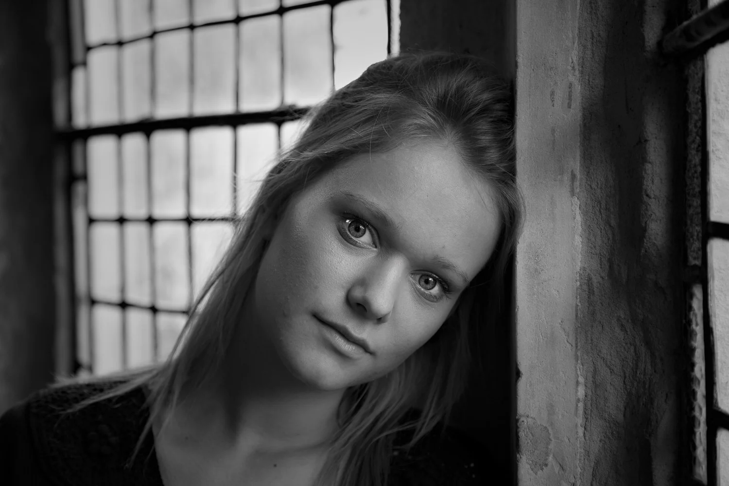 Lovely, delicate black and white portrait of young woman by window light.