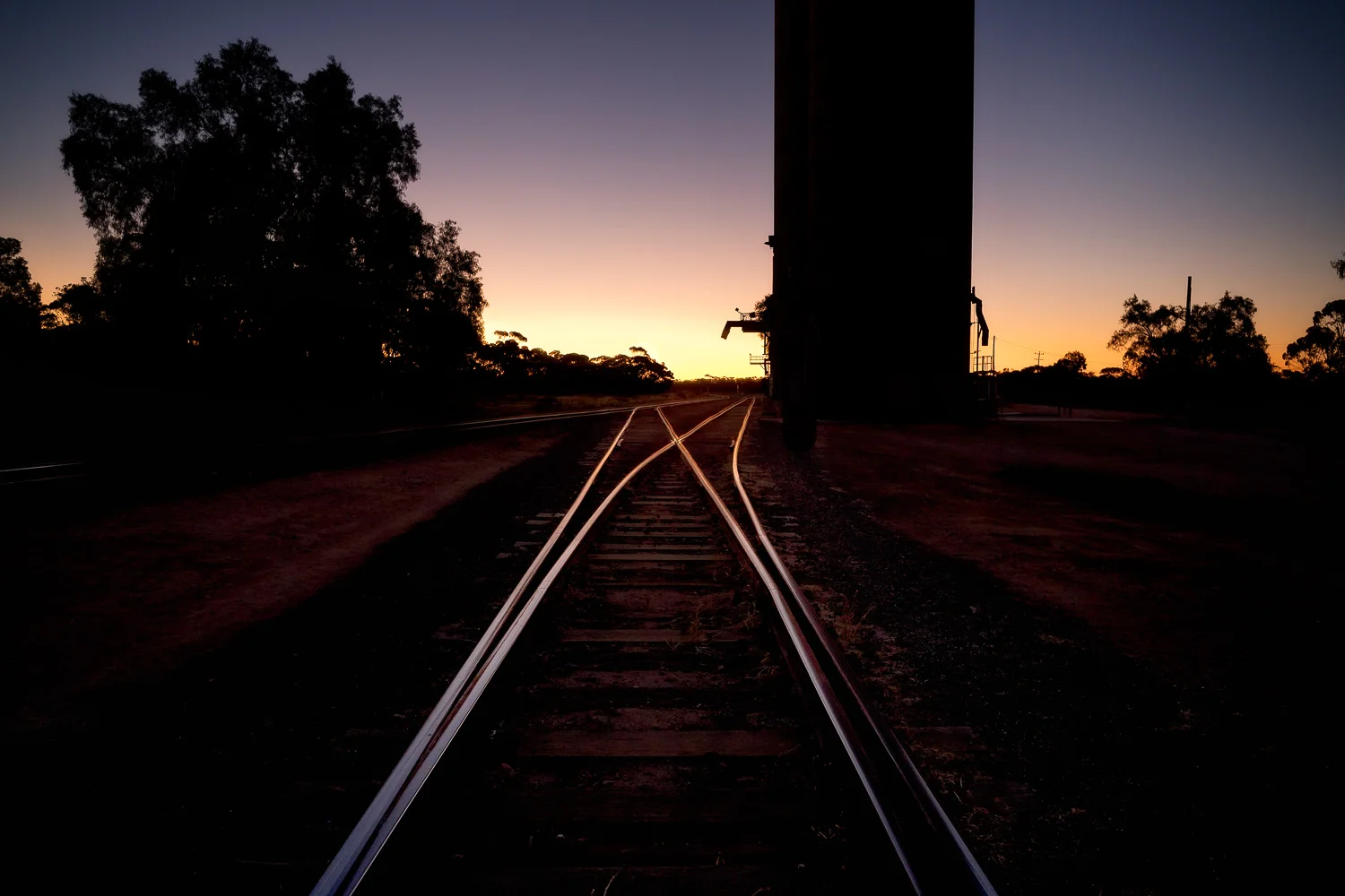 The light of the afterglow illuminates the tracks at the Murrayville Railway Station in the Sunraysia region of Australia .