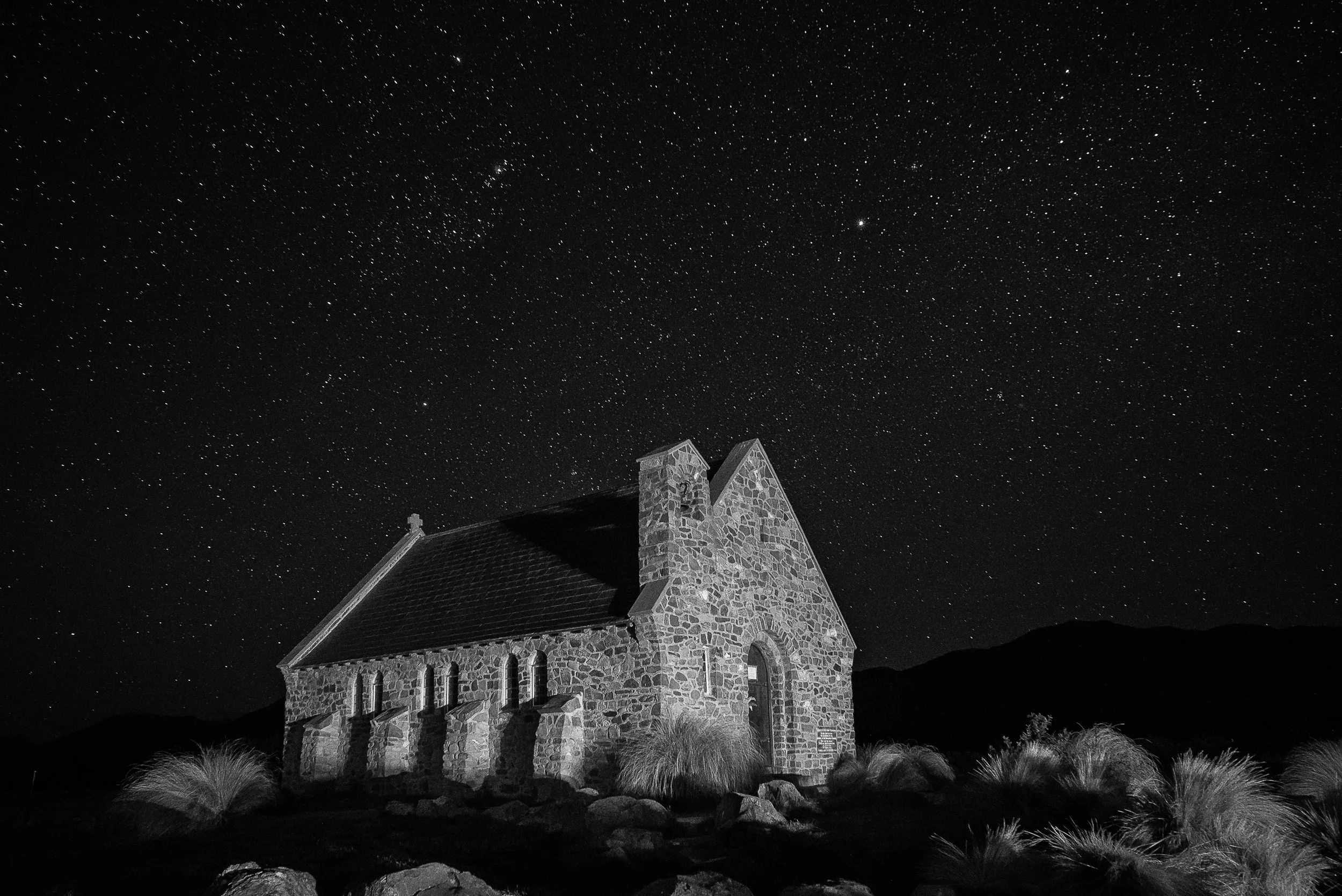 A black and white night photogaph of the lovely Church Of The Good Shepherd in Lake Tekapo , New Zealand .
