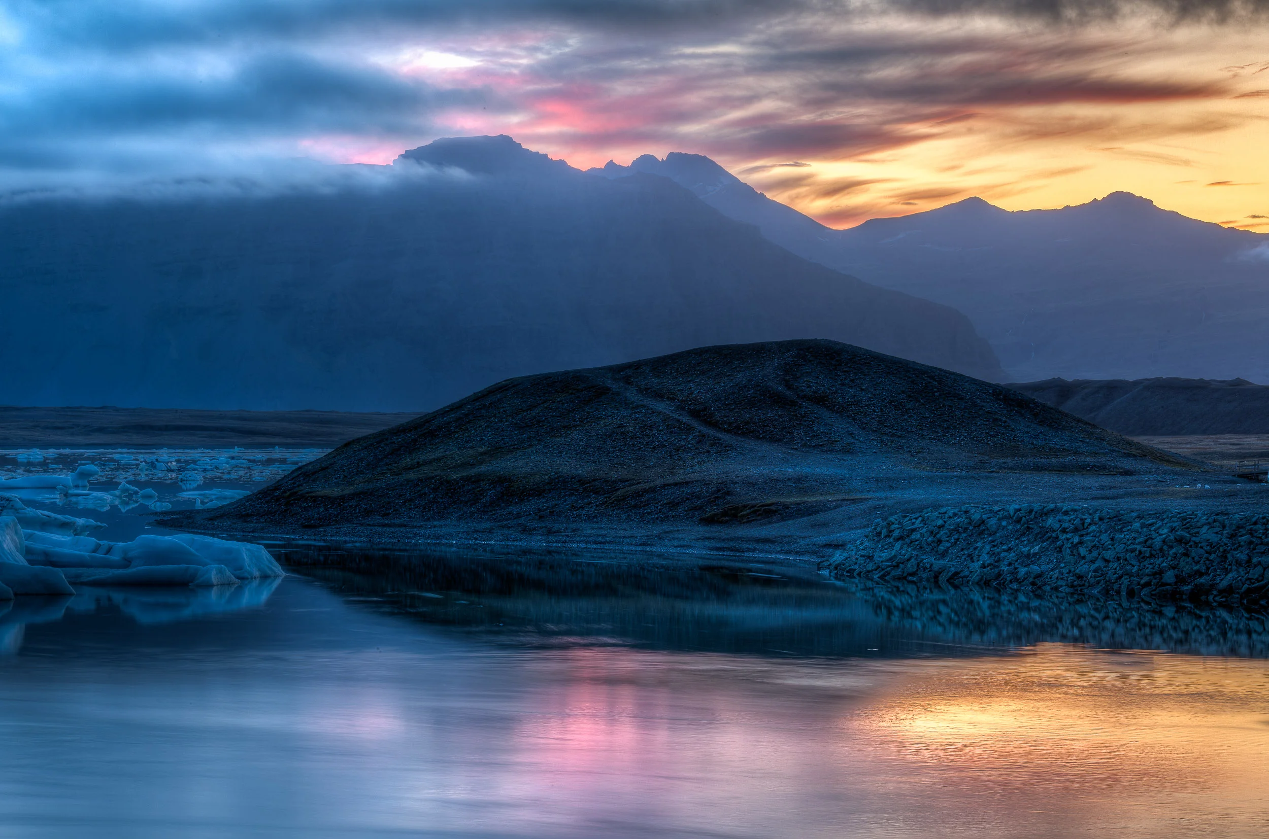 A beautiful glow at sunset illuminated the sky and water with a myriad of color at Jokulsarlon Glacier Lagoon in Iceland .