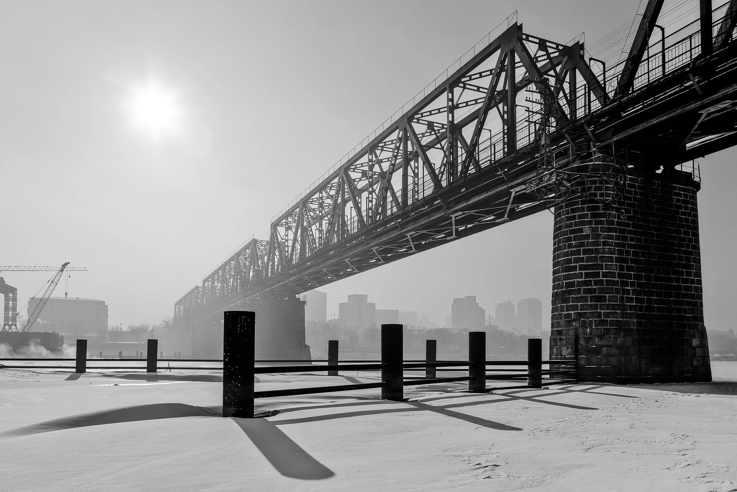 A rail bridge, in silhouette, on an overcast winter's day in Harbin, China . The strong graphic shapes and shadows make for a dramatic image.
