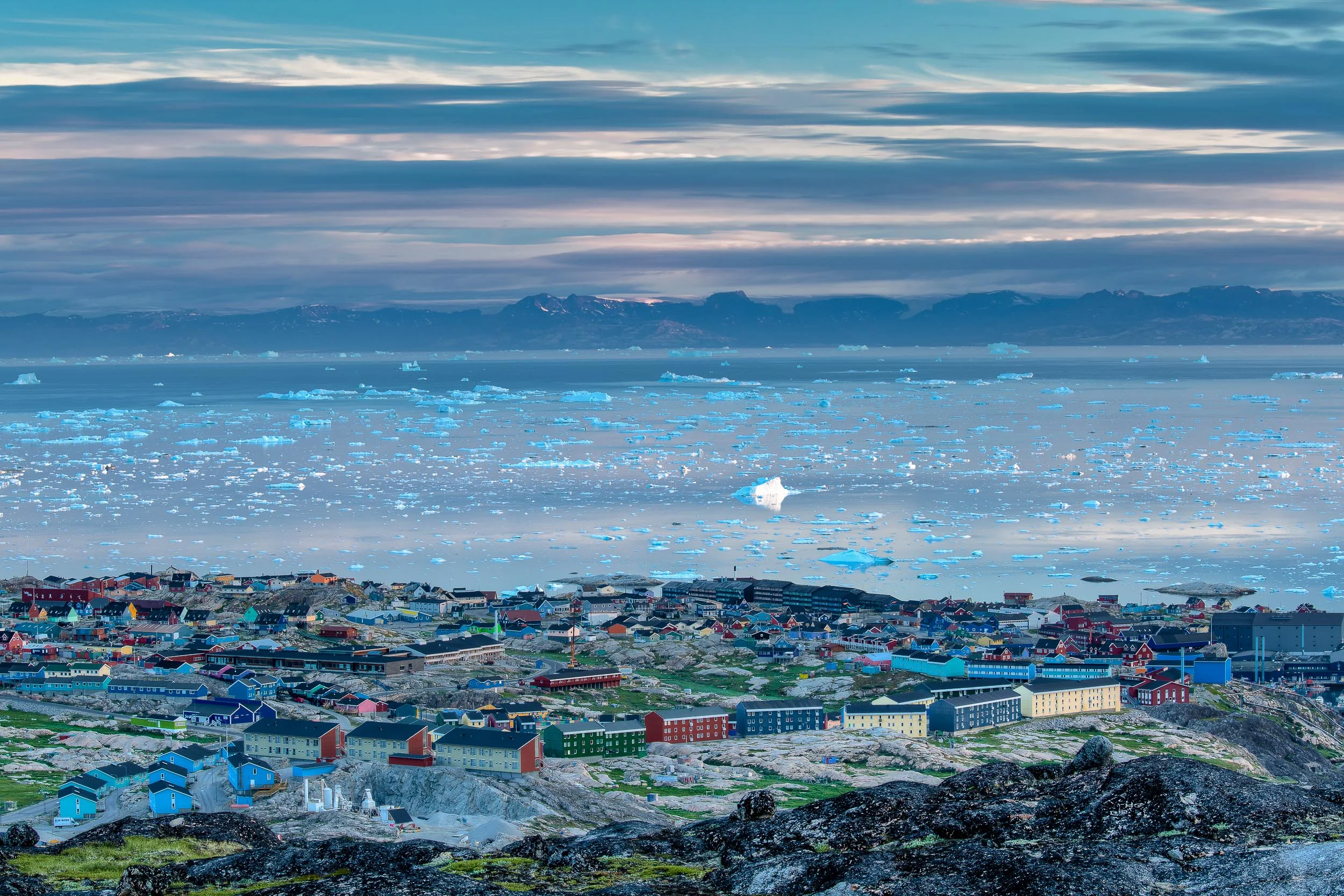 A view over the town of Ilulissat out over Disko Bay towards distant mountains, Greenland .