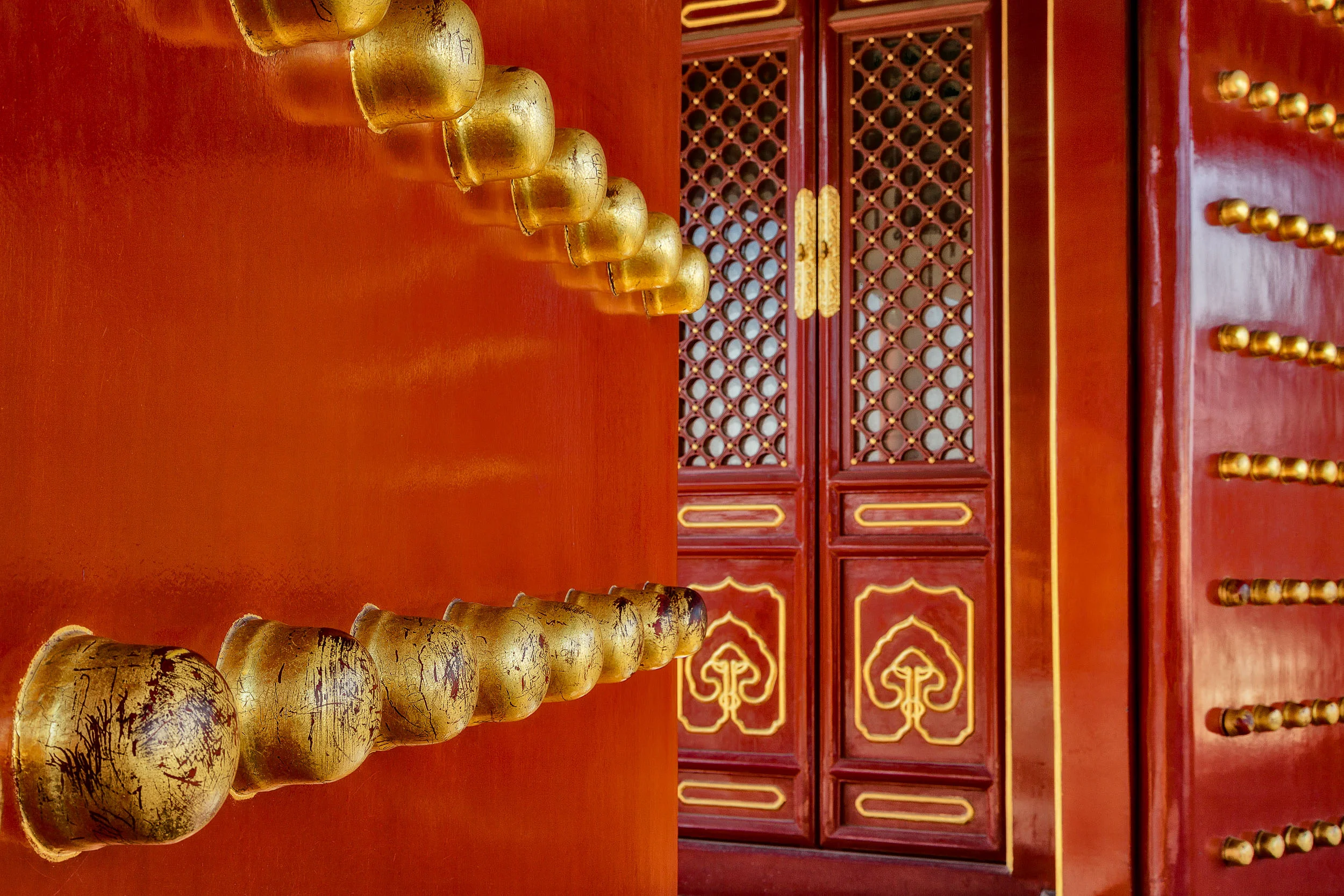 Large brass knobs lead the eye to a fabulously decorated door at the Temple Of Heaven in Beijing, China .