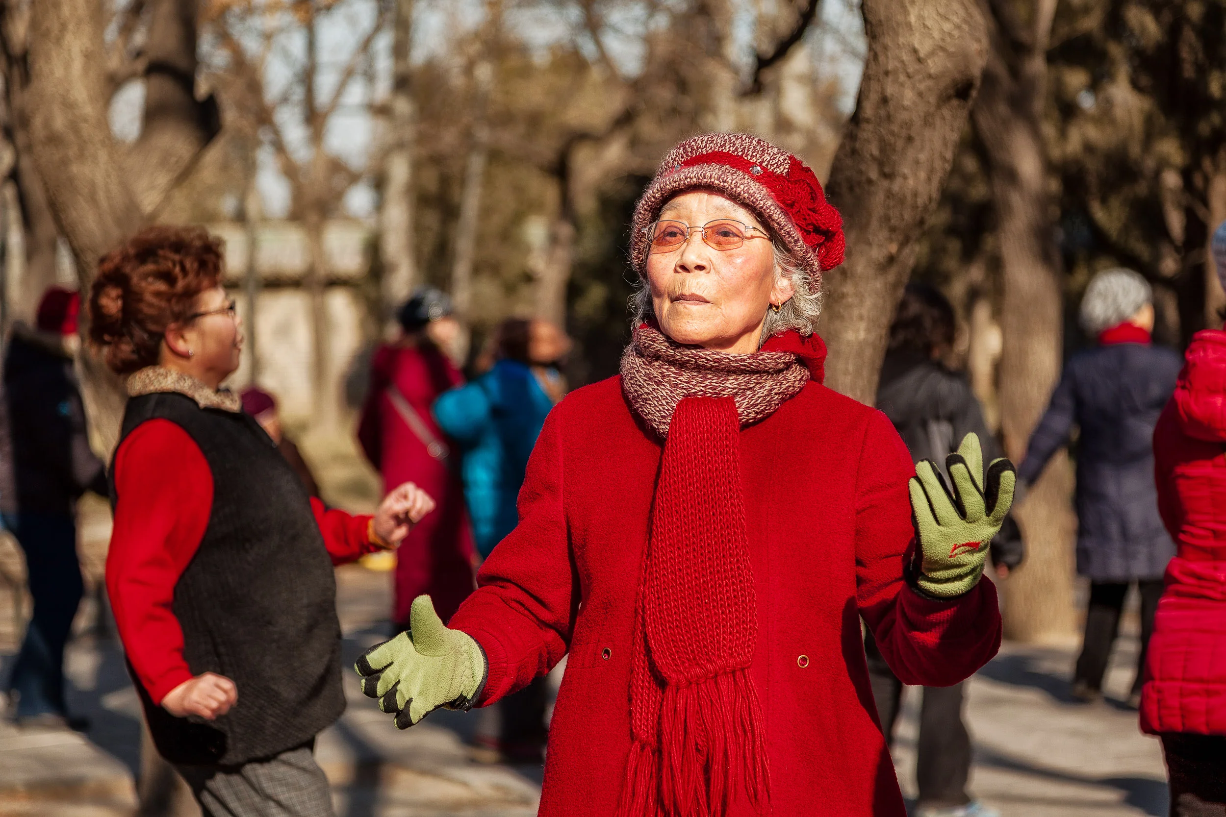 A group of elderly women dancing in the grounds of the Temple Of Heaven , on a winter's day, in Beijing, China .