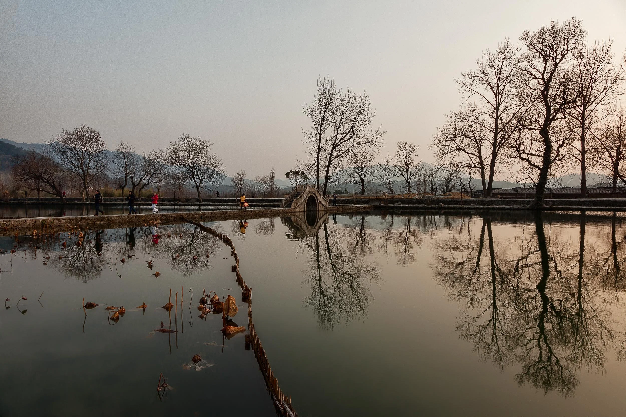 Trees and people reflected in a pool of water at the village of Hongcun in Anhui Province, China . 