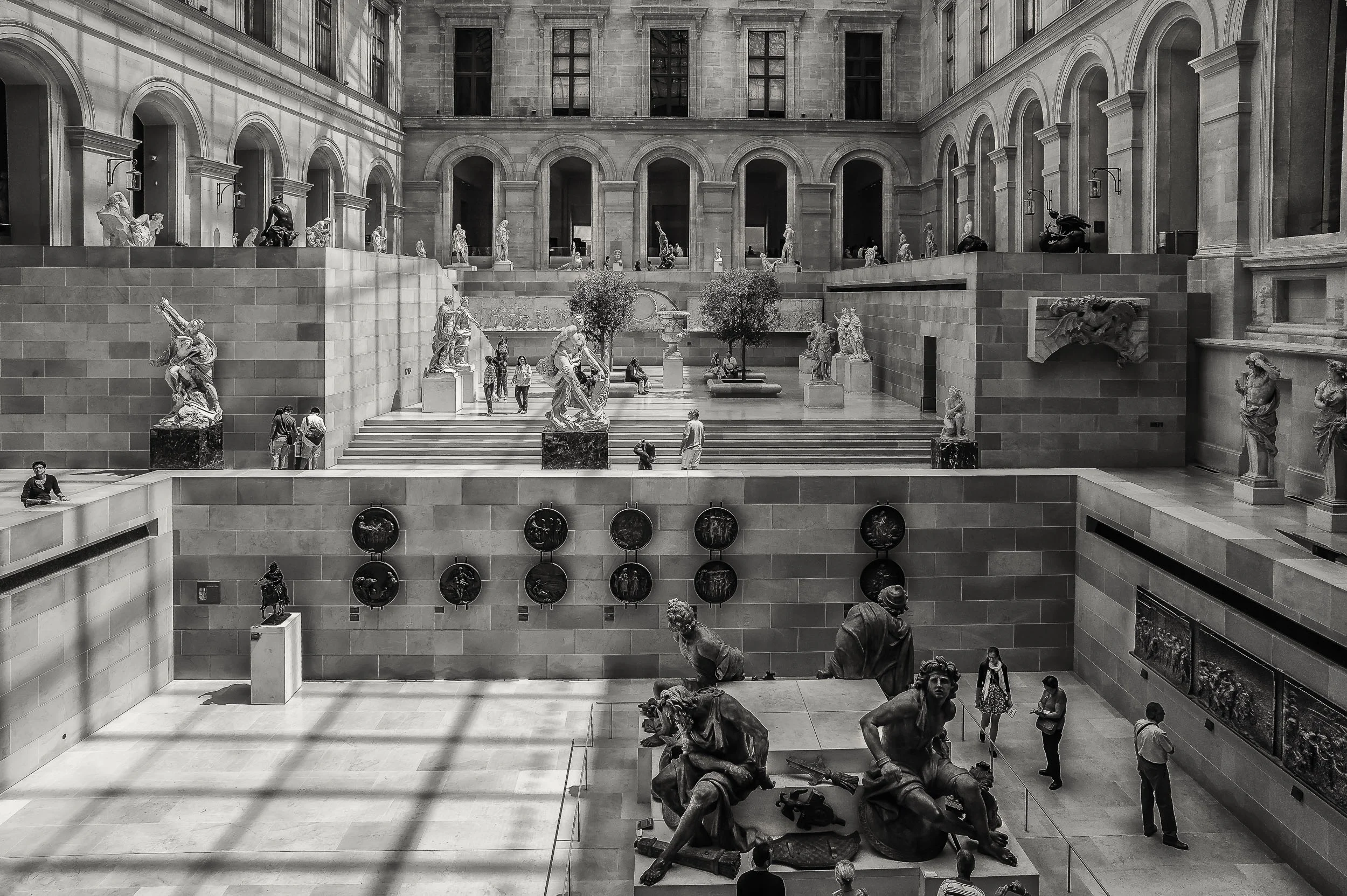 Visitors exploring an amazing space within the Louvre museum in Paris, France . This image explores light, tone and shape to help tell the story.