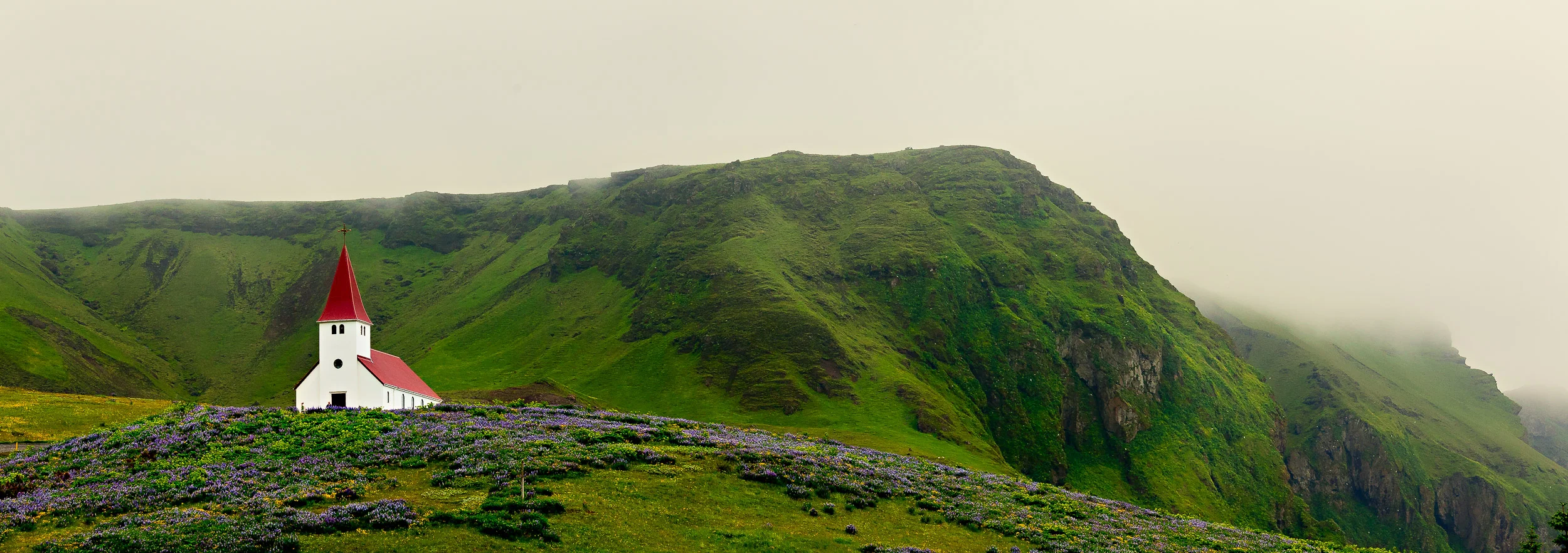 A spectacular panoramic view of the Vik Luthern Church on a hillside above the town. At around 300 inhabitants Vik is the southern most town in Iceland .