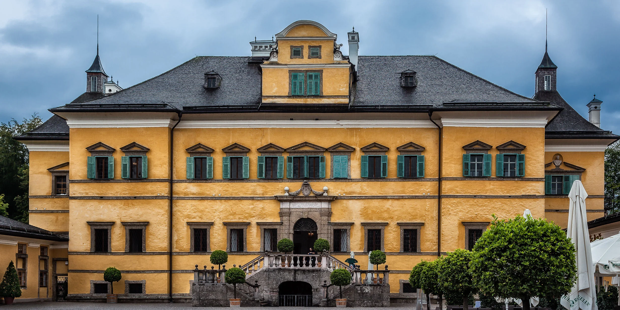 The butter yellow exterior of this mansion on the outskirts of Salzburg, Austria is offset with vivid green window shutters .