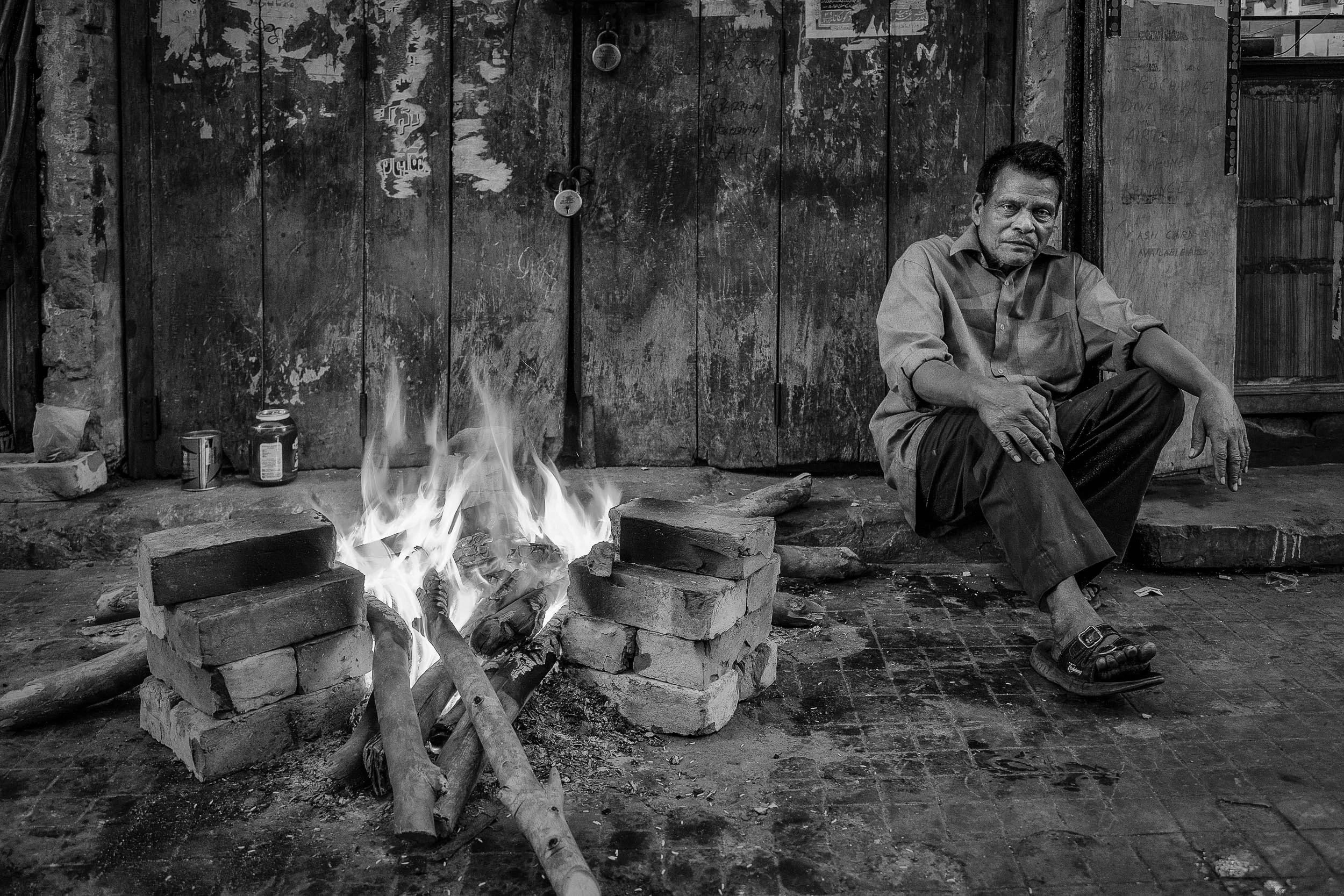 A man sits by a fire in the back streets of Kolkata, India.
