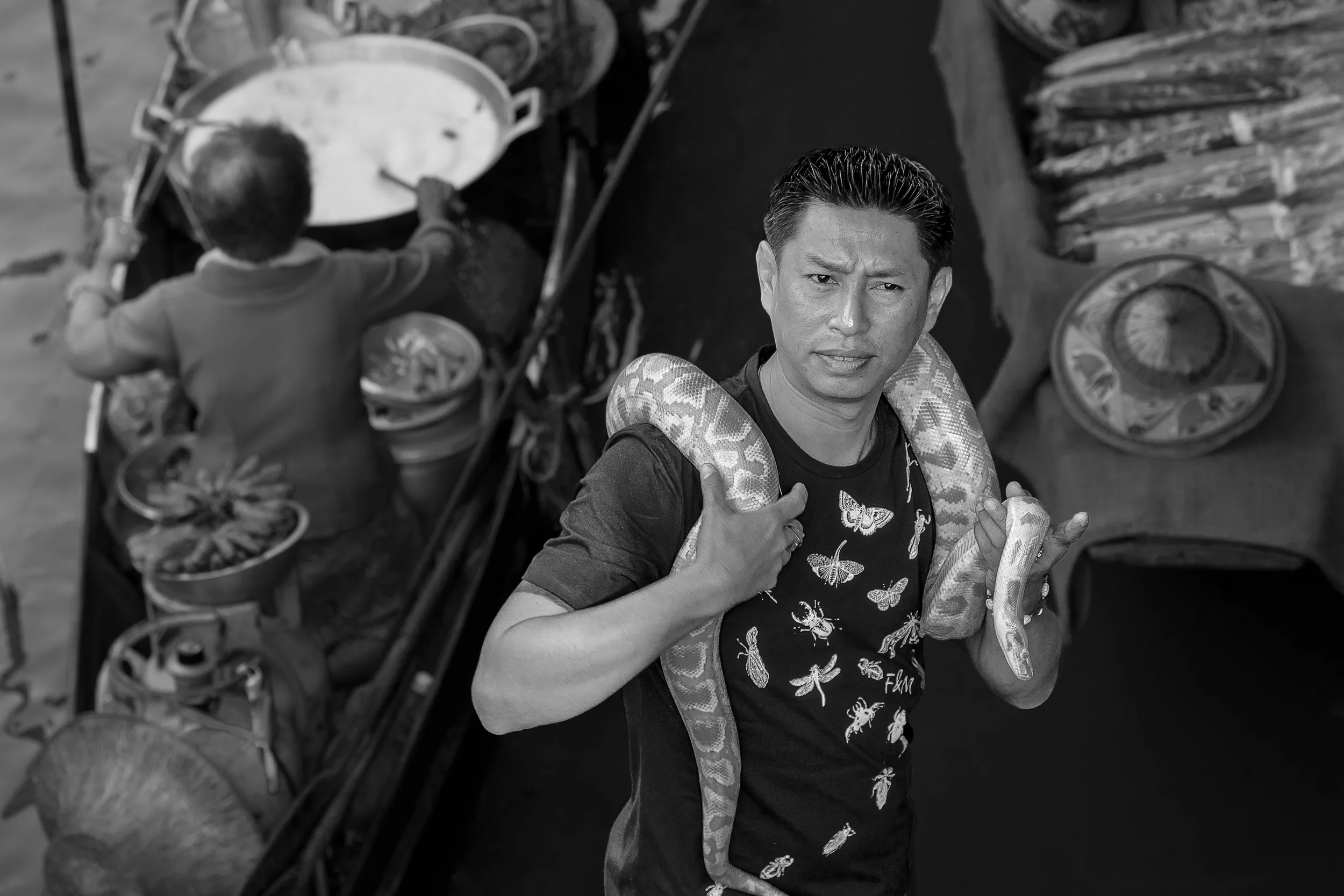 A snake handler poses for photographs with a large, yellow python at the Floating Markets near Bangkok, Thailand .