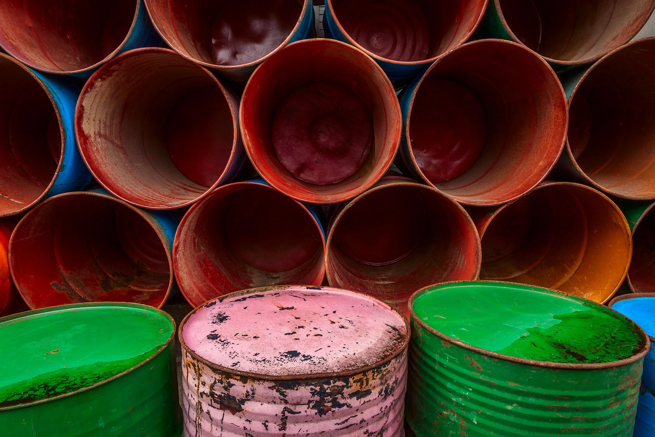 An arrangement of colorful barrels , stacked by the side of the road in Ubud, Bali make for a vivid and symmetrical composition .