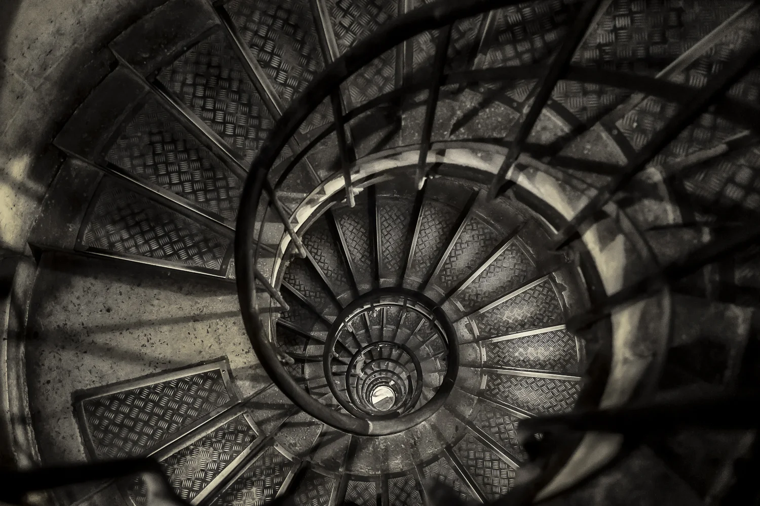 A moody birdseye view looking down a narrow stairwell at the Arc de Triomphe in Paris, France .