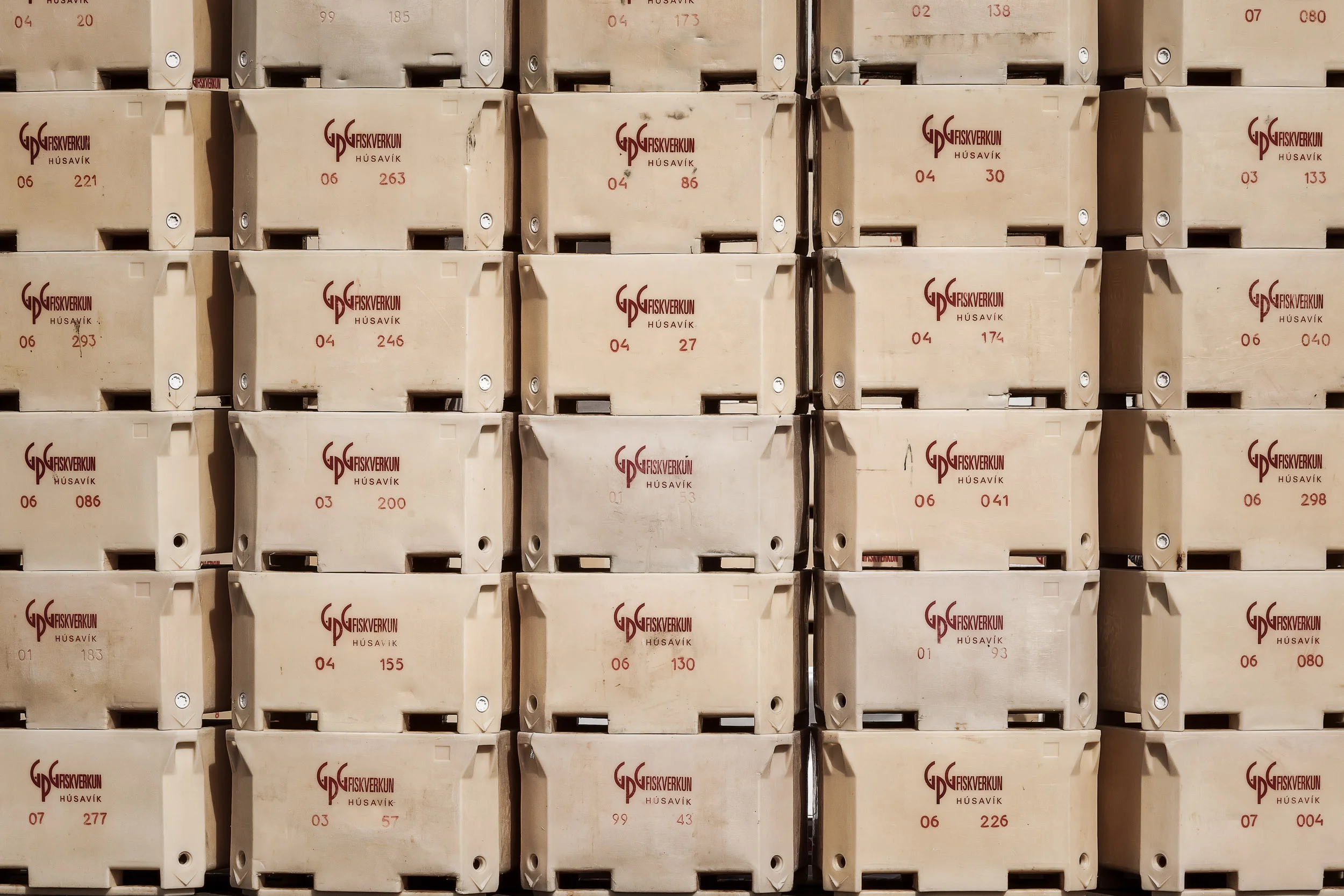 A wall of fish packing boxes on the wharf in Húskavík in northern Iceland .