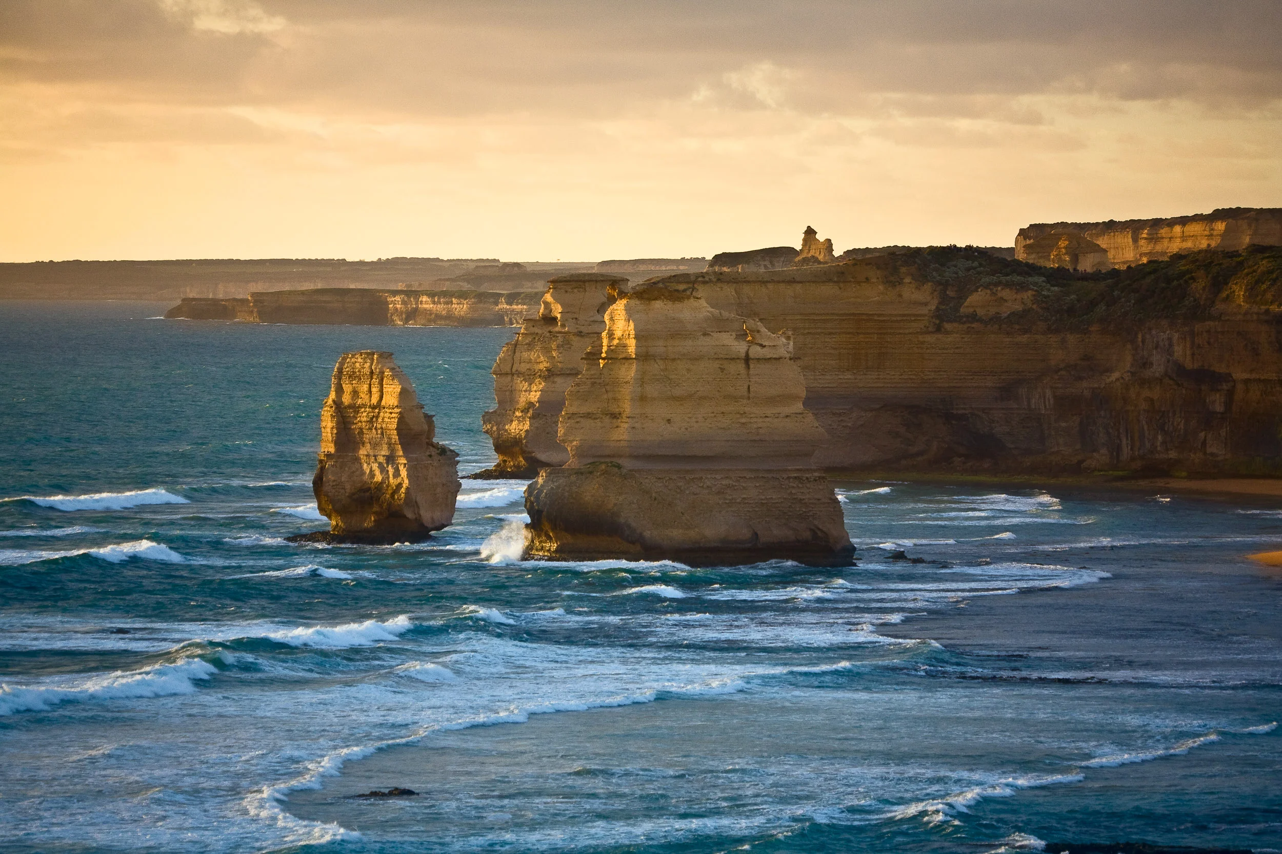 Warm light during the golden hour caresses the famous Twelve Apostles along Australia's Great Ocean Road .