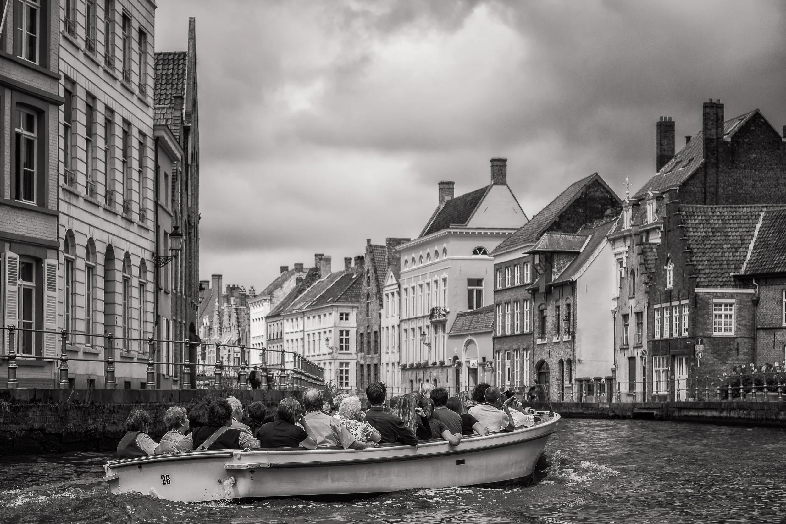 A group of tourists taking a small boat tour on the canal in Bruges (i.e., Brugge), Belgium .