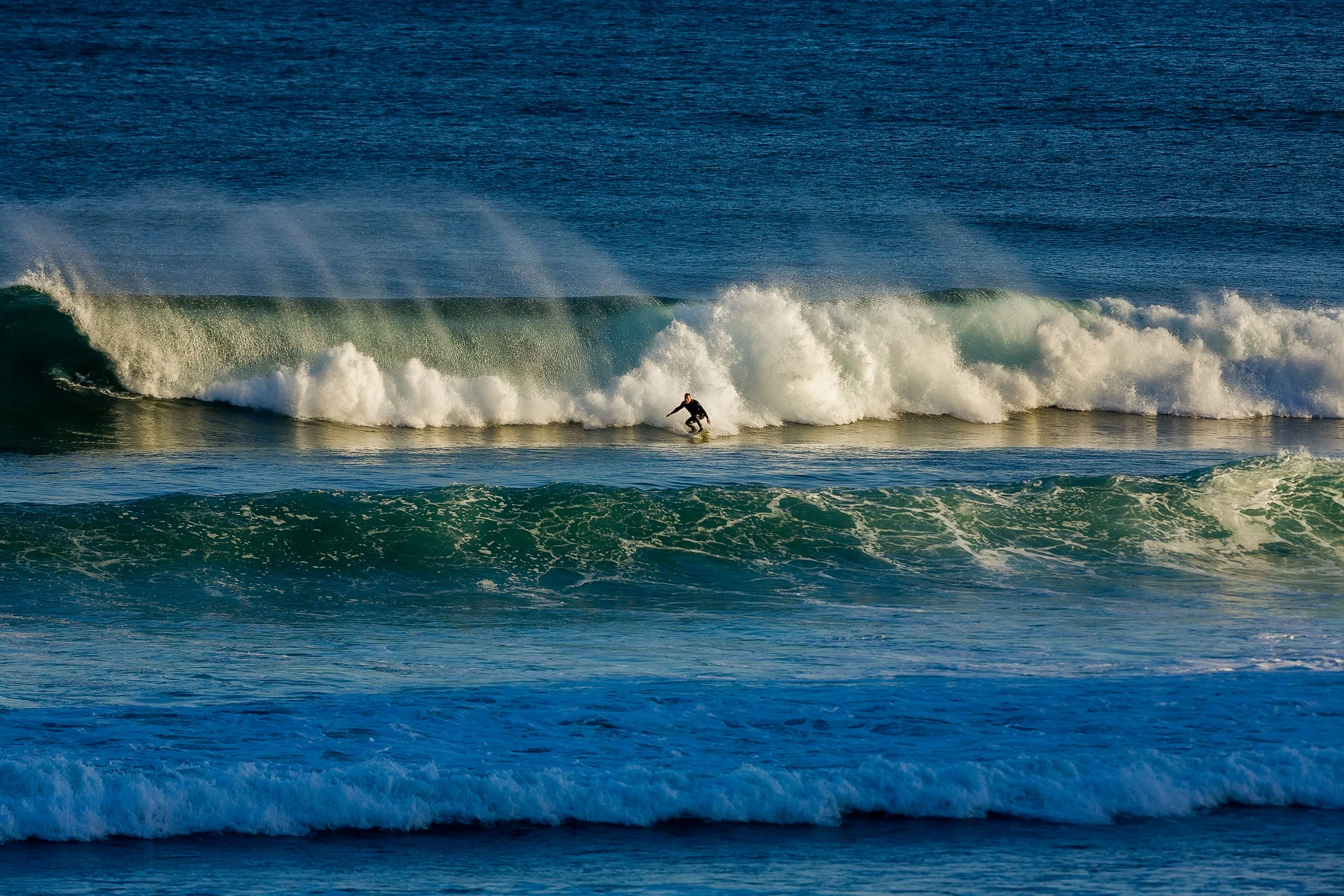 A surfer , catching the late afternoon rays at Bells Beach, Australia .
