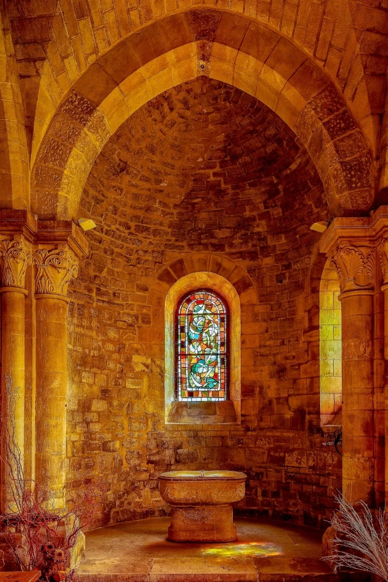 Light shines threw a stained glass window and adds streaks of color to the stone floor of a chapel in Paris, France .