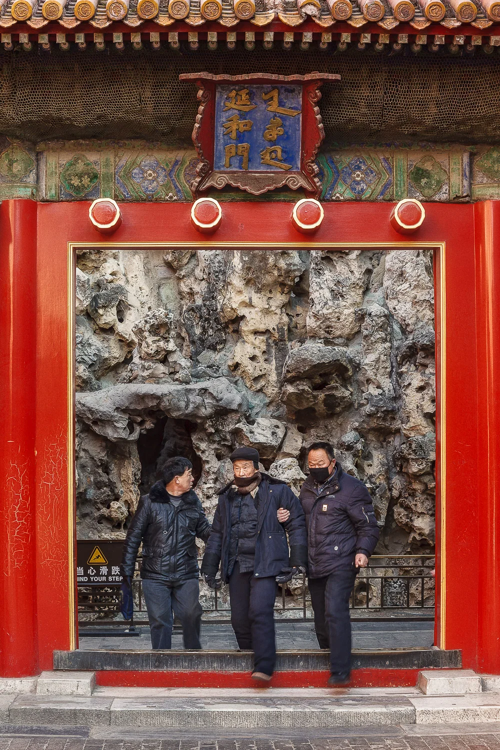 Three men moving through an inner gate within the Forbidden City, Beijing.