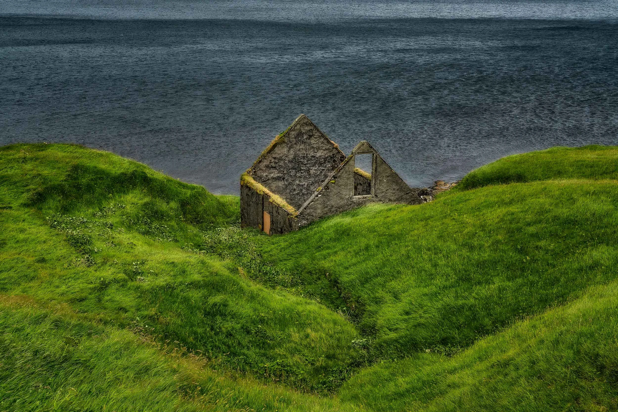 The ruins of a dwelling by the shores of the sea on the island of Eysturoy in the Faroe Islands .