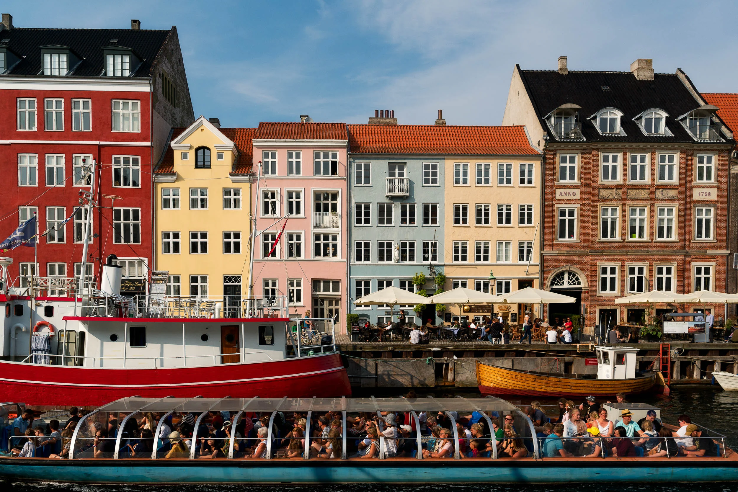 An incredibly colorful scene as a boat of tourists sail along the canal at Nyhavn in Copenhagen .