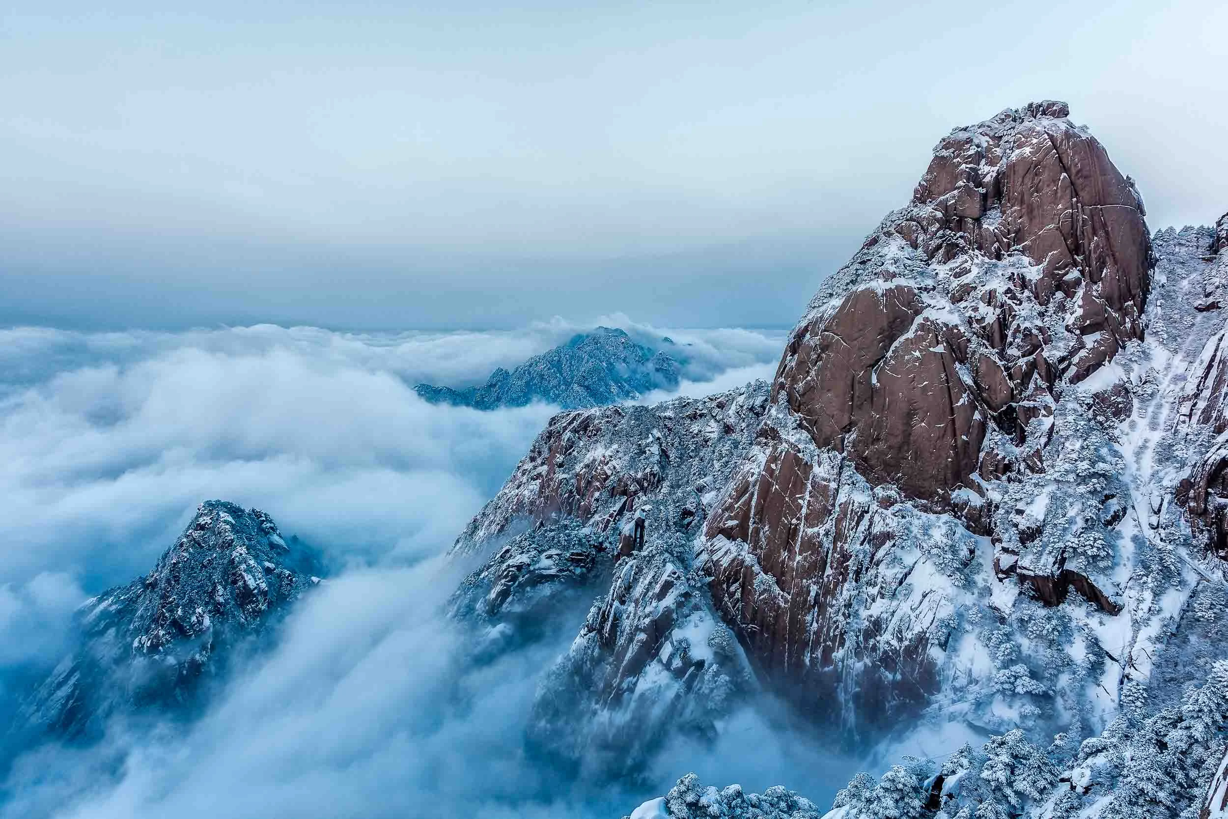 Dramatic photo of peaks, emerging through fog, on the sublime Huangshan Mountain.