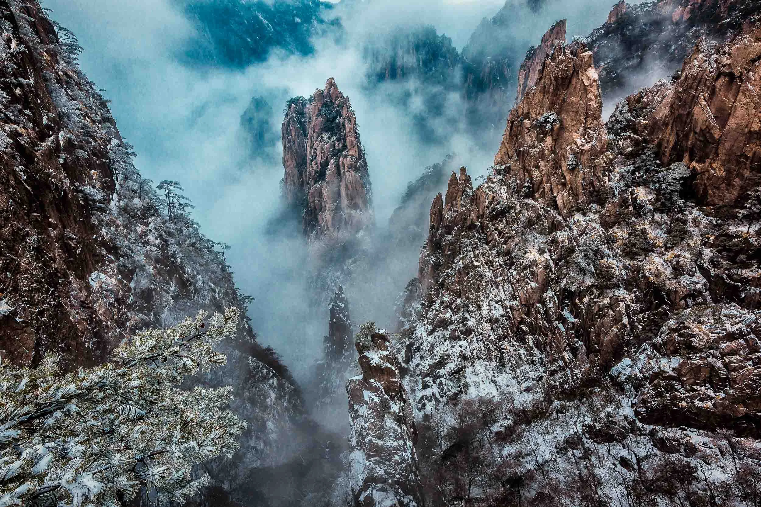 Mist swirling around peaks of stone on Huangshan (i.e., Yellow Mountain), China .