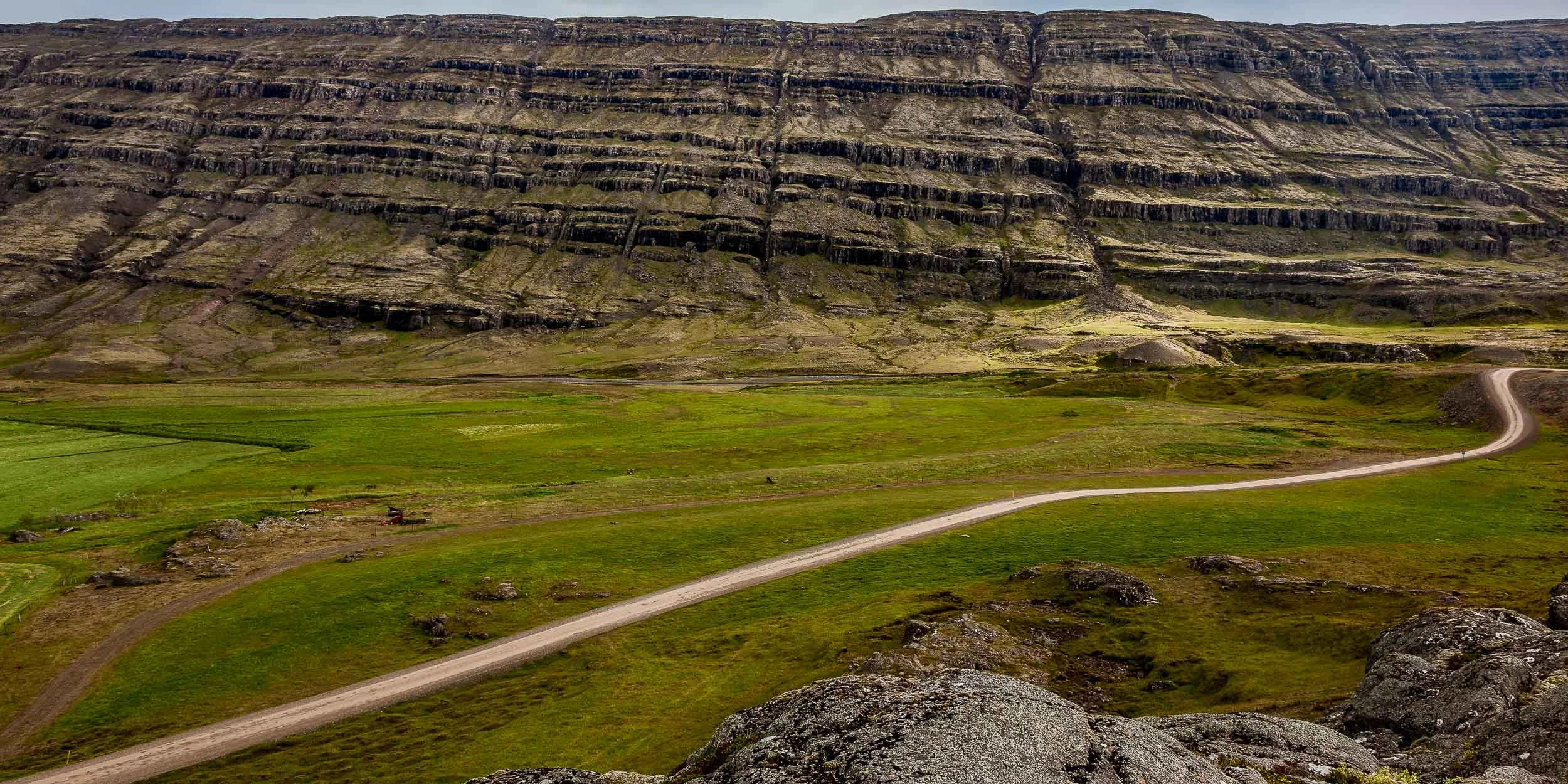 Dirt road winds its way through beautiful mountain scenery in rural Iceland.