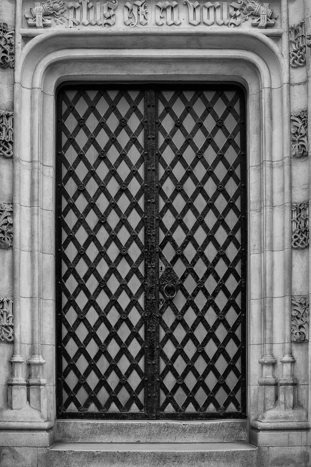 Metal and wood lattice door, framed by stone, in Bruges, Belgium.